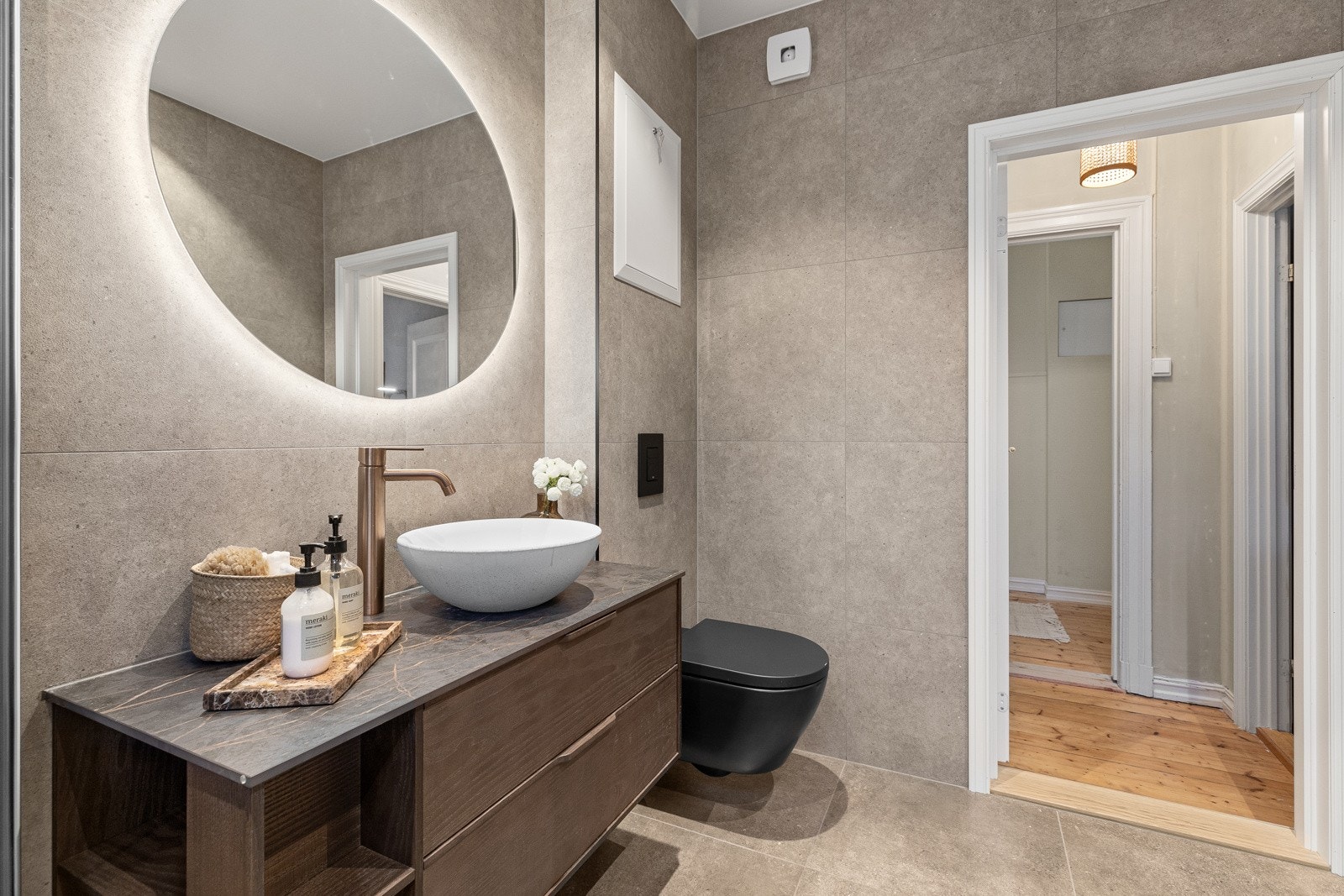 Svart, vegghengt toalett fra Villeroy & Boch, samt Silhouet servantkran i børstet kobber. Epos benkeplate Laurent Galleribilde