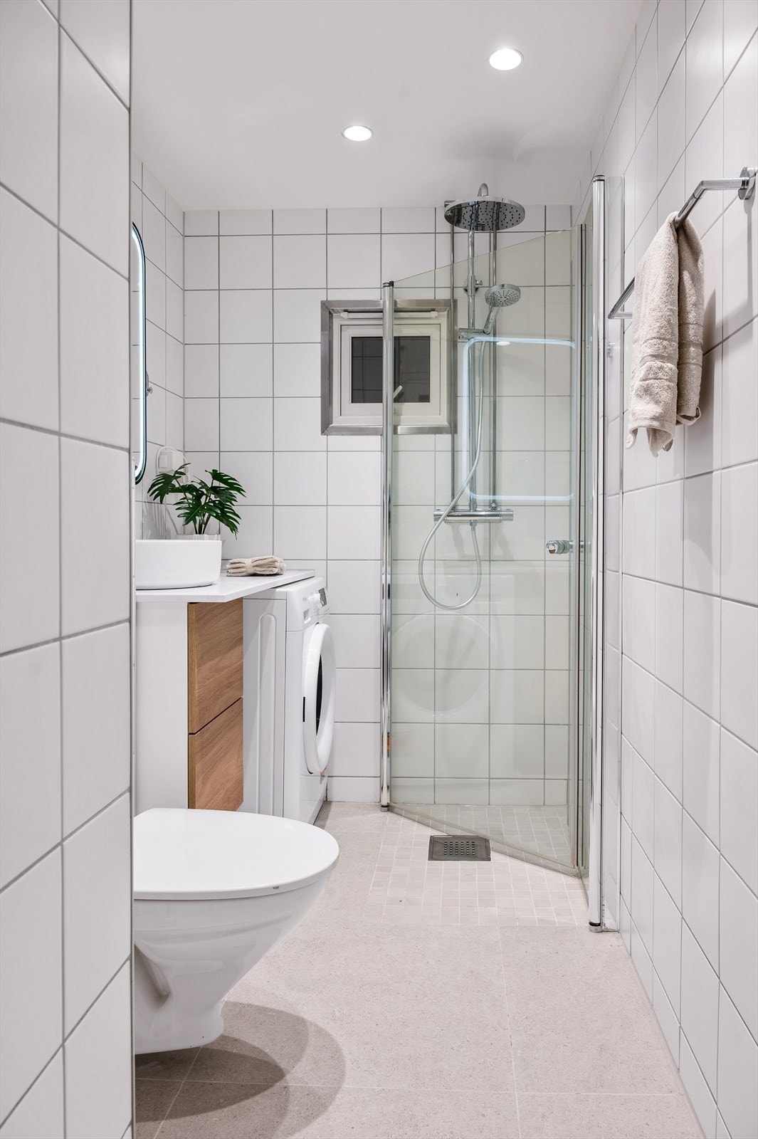 Badet består av dusjhjørne, opplegg for vaskemaskin, servant med oppbevaring og toalett Galleribilde