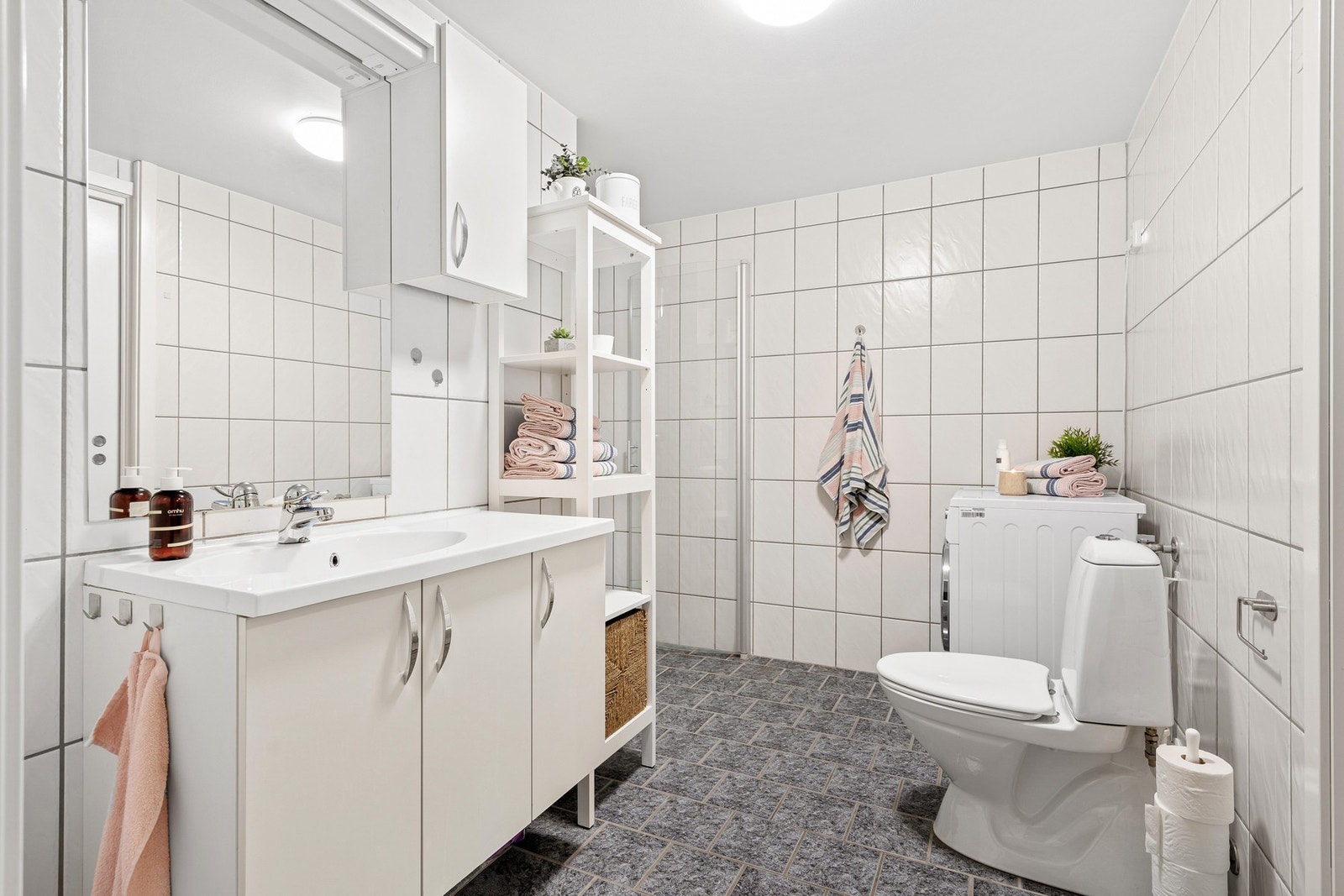 Lyst flislagt baderom med opplegg for vaskemaskin. Galleribilde