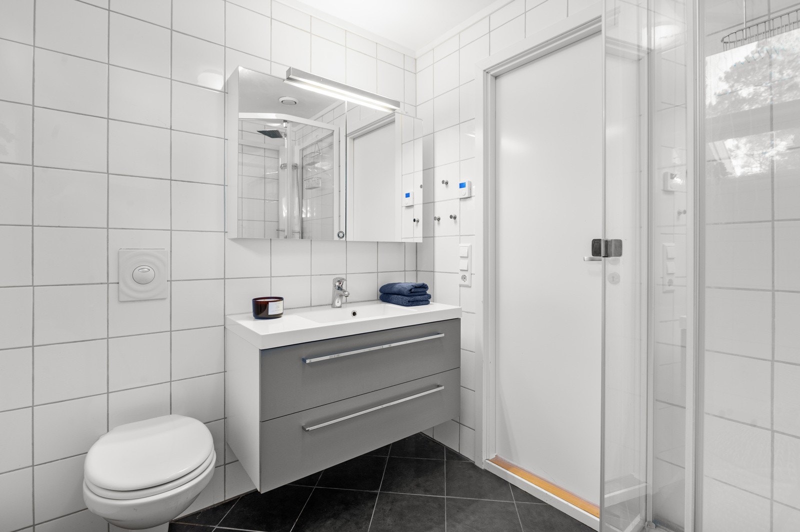 Hovedbadet har tidløse fliser og er innredet med servantskap, dusjhjørne og vegghengt wc. Galleribilde