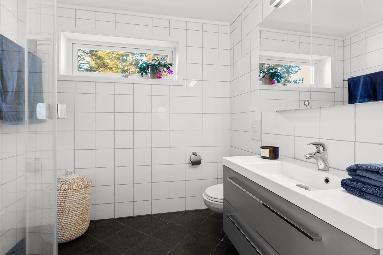 Hovedbadet har tidløse fliser og er innredet med servantskap, dusjhjørne og vegghengt wc. Galleribilde