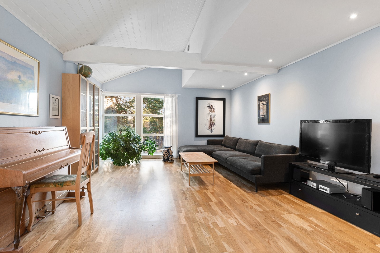 Stuen har mye naturlig lys inn fra de store vinduene og takvinduene i spisestuen. Galleribilde