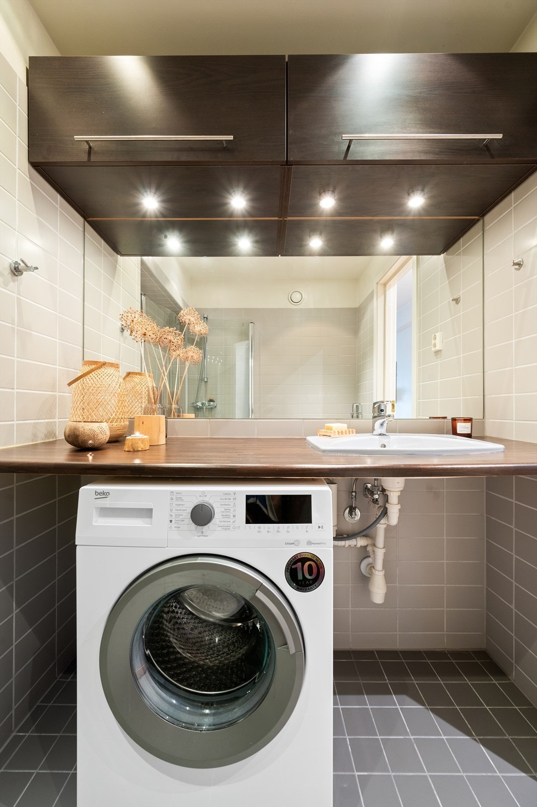 Innredningen består av nedsenket servant og vegghengt speil med overbelysning og overhengende skap med plass til oppbevaring. Vaskemaskinen medfølger leiligheten. Galleribilde