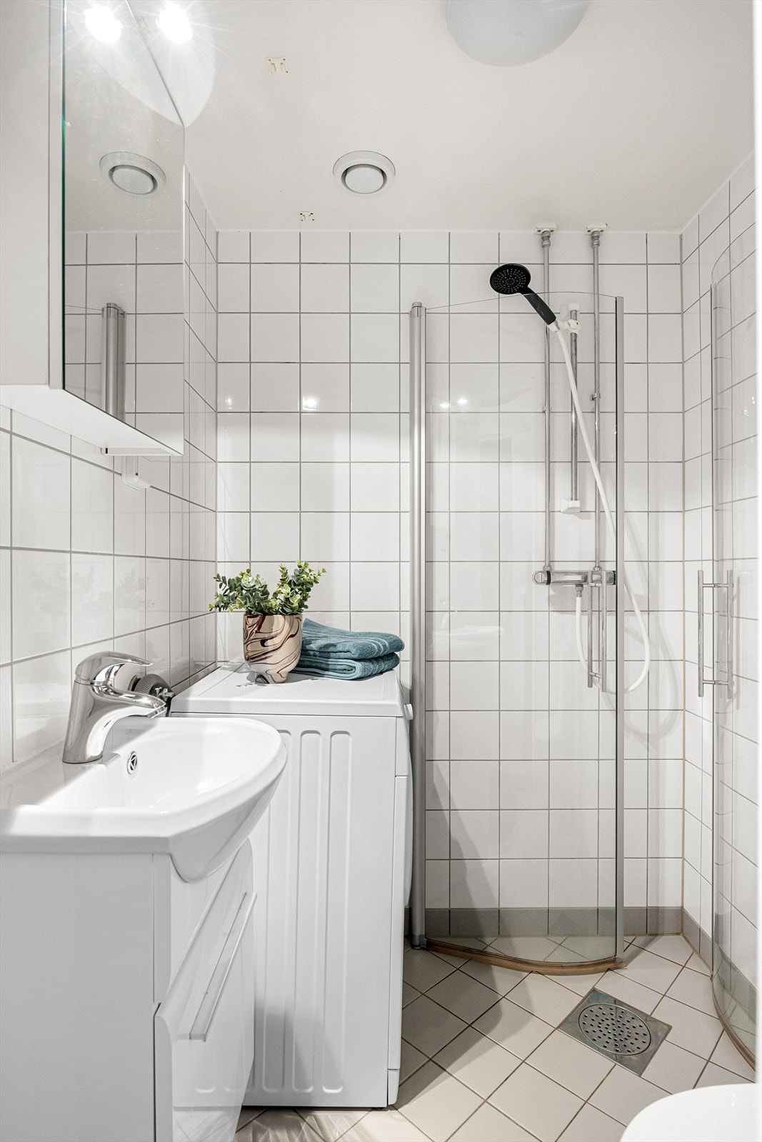 Badet er innredet med klosett, servant på innredning, speilskap med lys og dusjhjørne med svingbare glassdører. Galleribilde