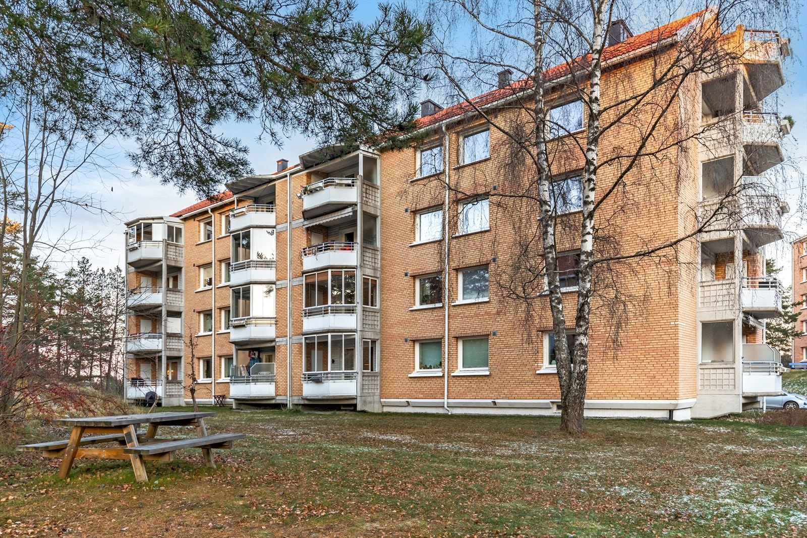 Stor felles tomt, opparbeidet med asfalterte adkomstveier/plasser, gressplen, beplantning, trær, lekeapparater, parkeringsarealer m.m. Galleribilde