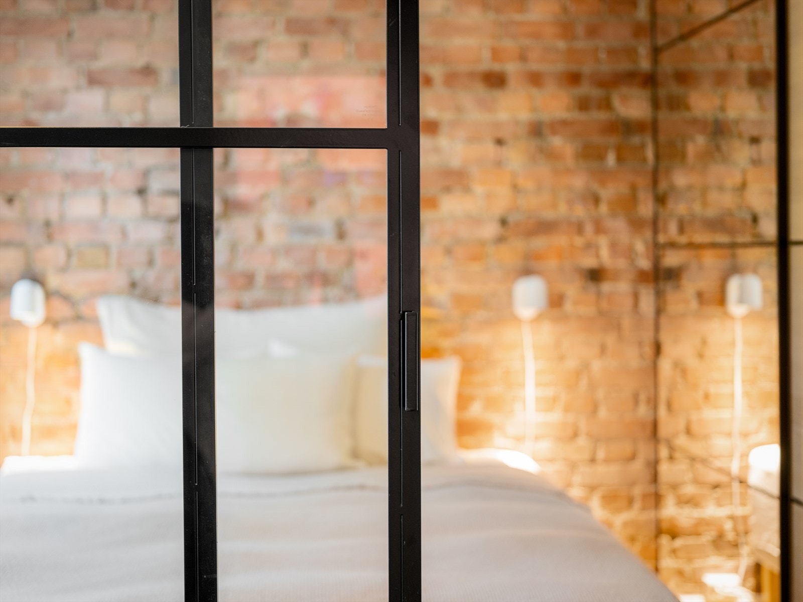 Glassveggen i sort stål tilfører leiligheten et tøft industrielt utrykk. Skyvedøren gir god mulighet for å separere soverom og stue når man selv ønsker. Ønsker du mer skjerming mot stuen kan en gardin i takskinne henges på innsiden. Galleribilde