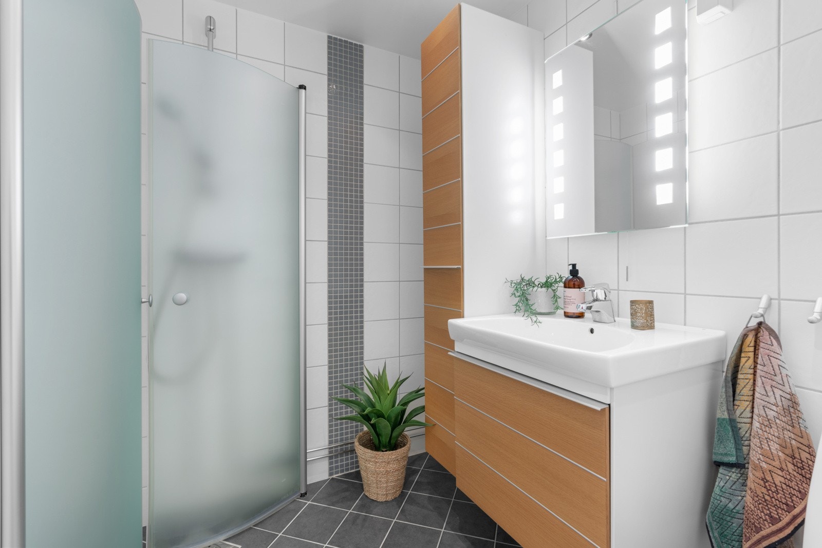 Downlights og varmekabler er installert, og badet har toalett og et dusjhjørne med innfellbare glassdører i buet utforming. Det er felles vaskeri i inngangsetasjen. Galleribilde