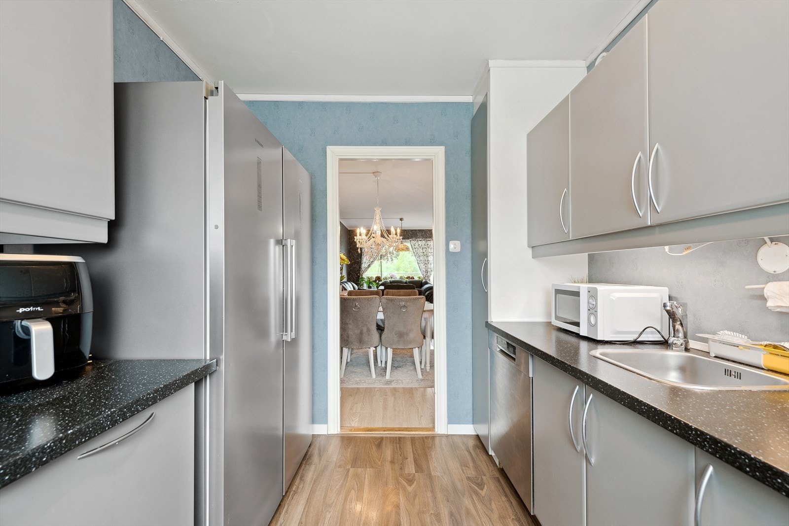 Moderne kjøkken med hvitevarer og åpen dør mot spiseplass Galleribilde