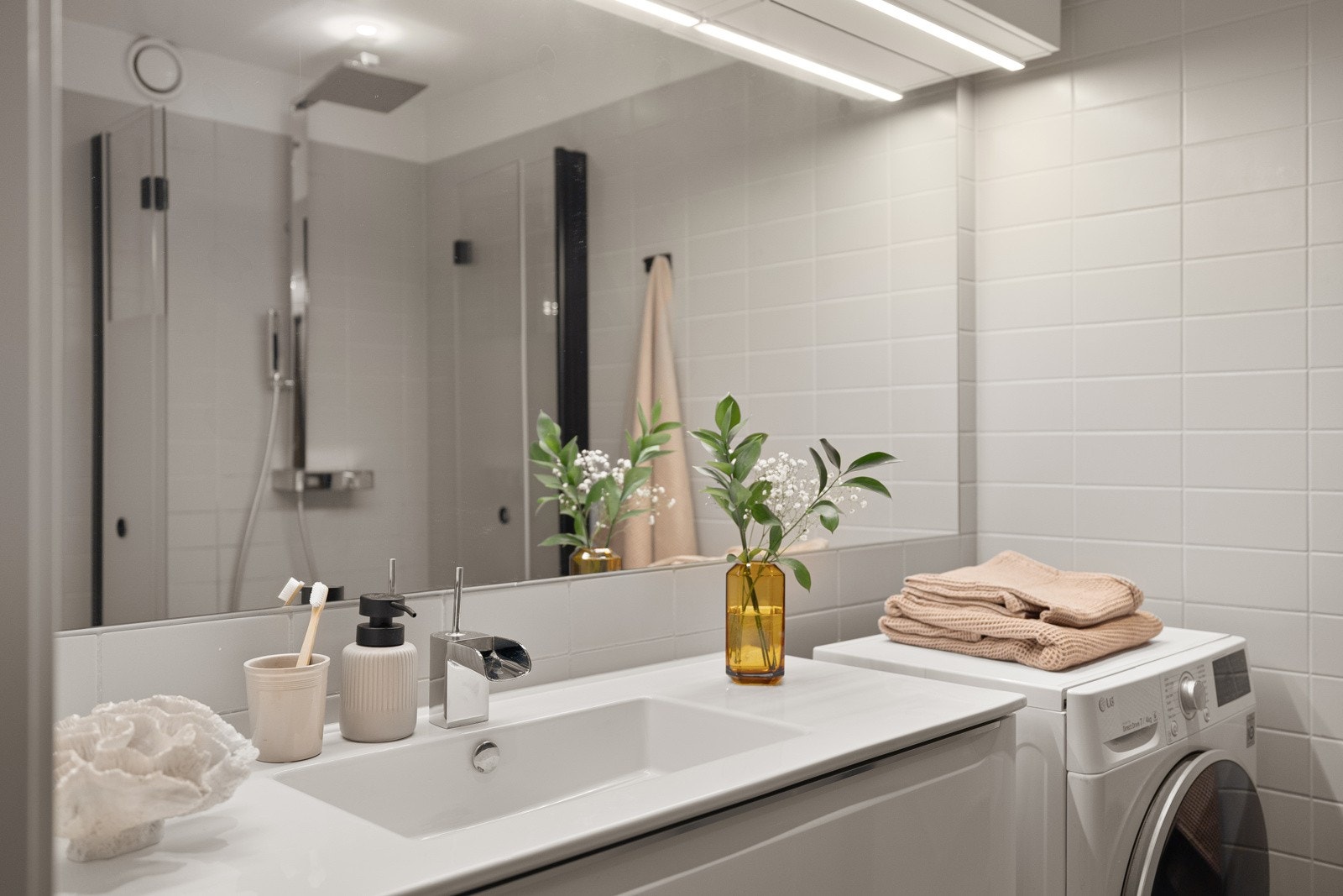 Vegghengt servantinnredning med glatte, lyse fronter og vegghengt toalett med sisternekasse. Galleribilde