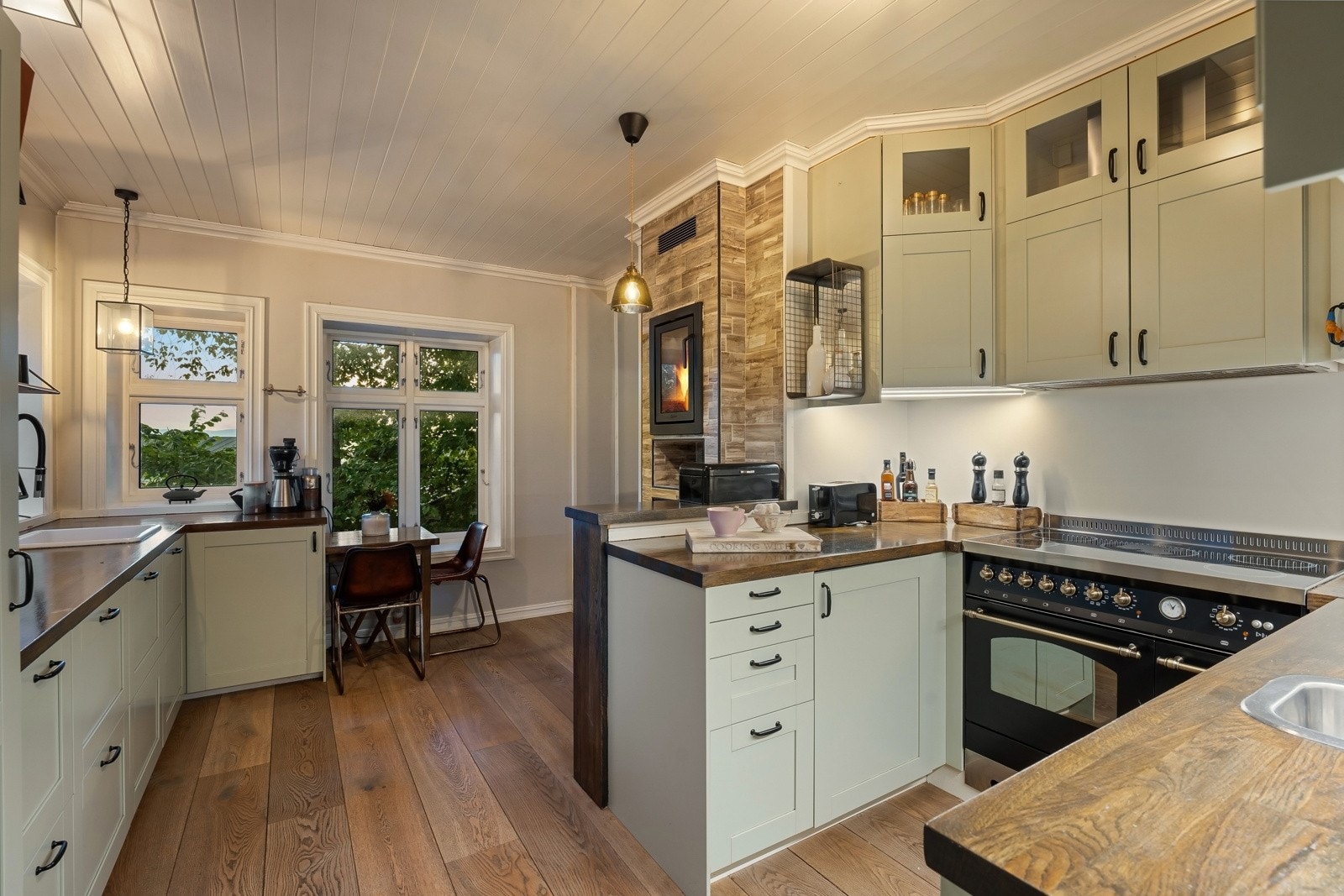 Innredningen har lyse, profilerte fronter, vitrinedører, takhøye skap og solid heltrebenkeplate Galleribilde