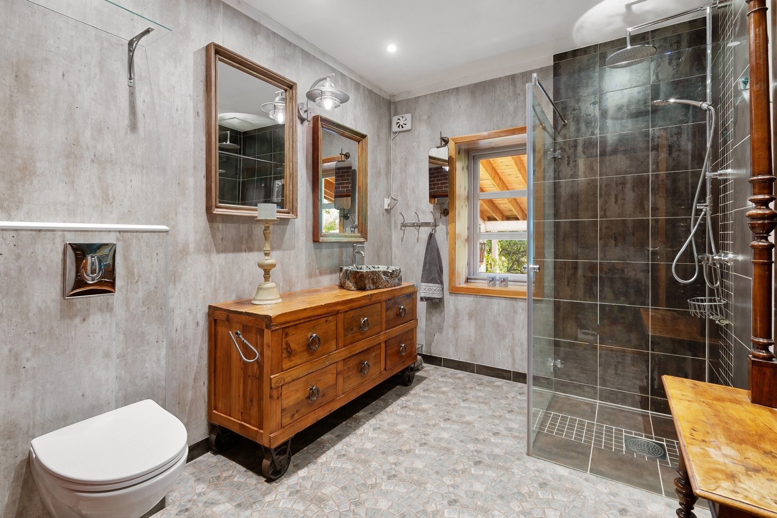 Våtromsplater i betong-look på veggene, downlights i himlingen og mønsterlagte fliser på gulv med gulvvarme Galleribilde