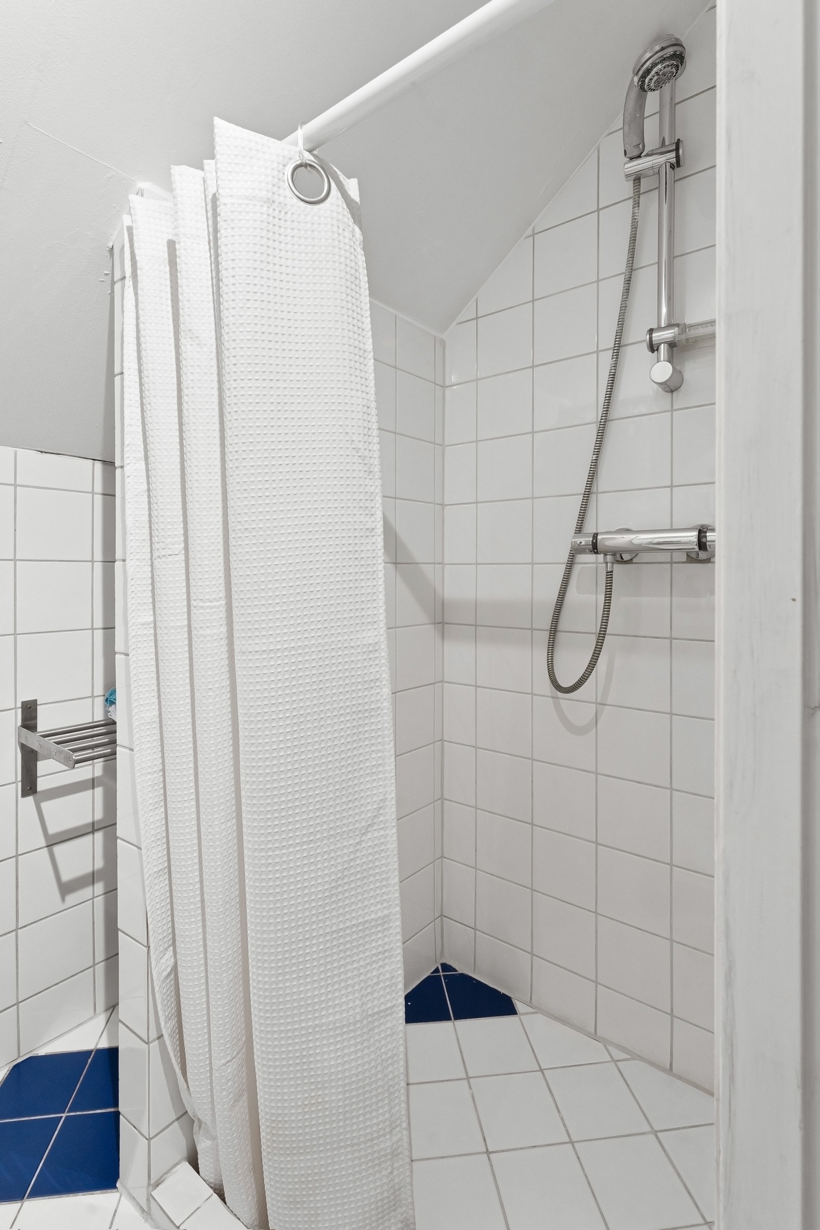 Her er det et gulvmontert toalett, en enkel servant og dusj Galleribilde