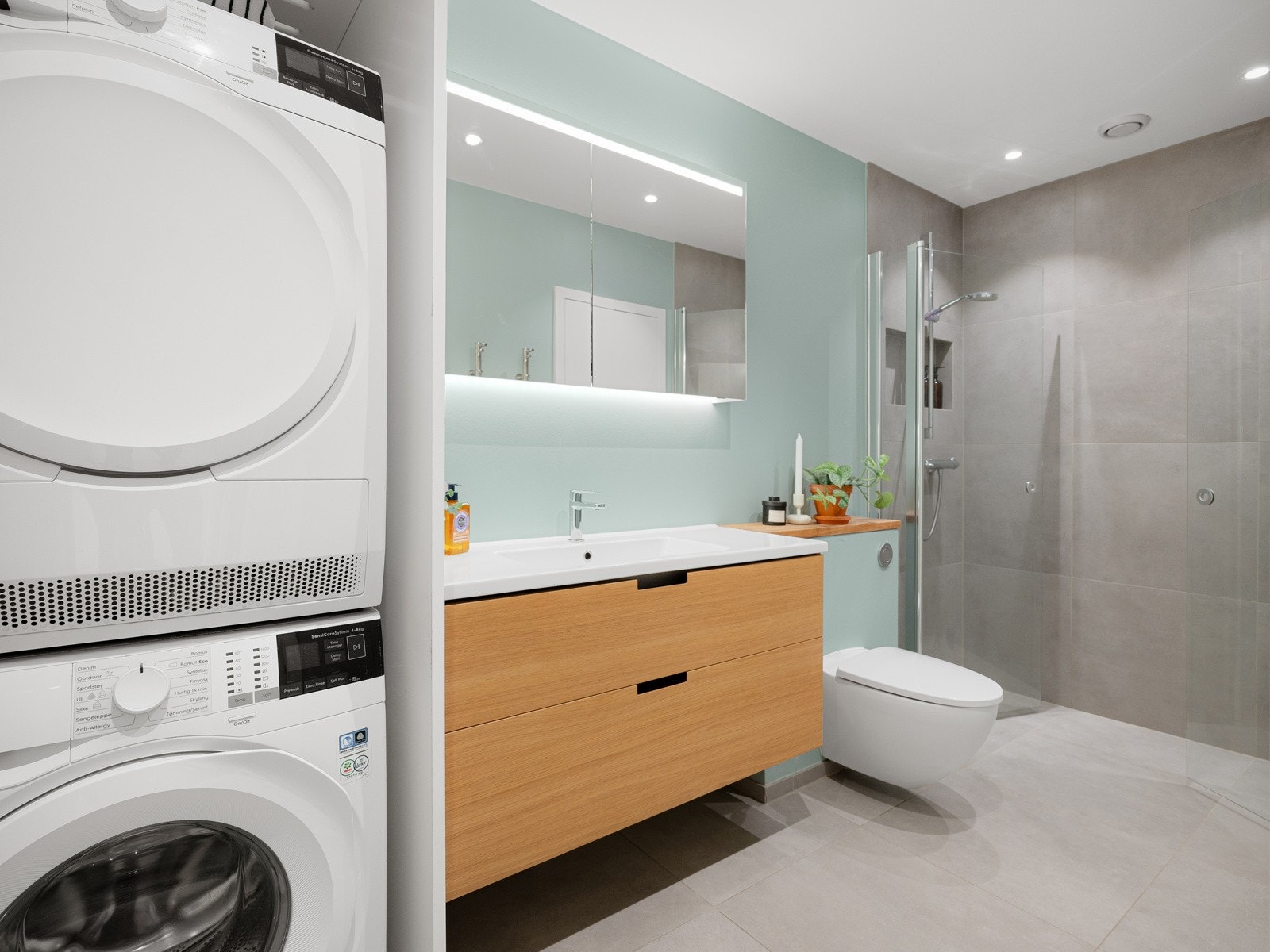 Det er både plass og opplegg for vaskemaskin. Dusjsone med glassdører og godt med albuerom. Galleribilde