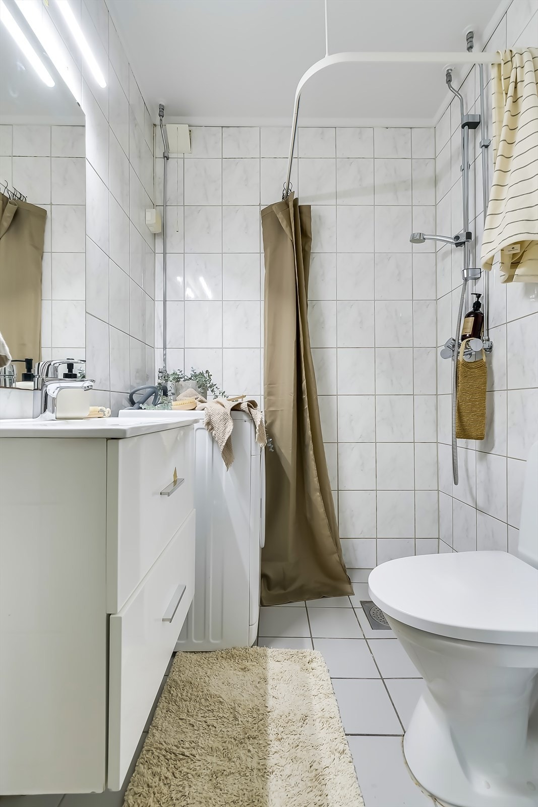 Badet er innredet med lyse fliser på vegger og gulv, som gir et tidløst uttrykk. Opplegg for vaskemaskin. Galleribilde