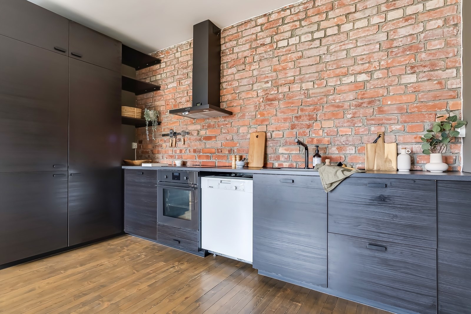 Lekker svart kjøkkeninnredning med slette fronter med håndtak og benkeplate av laminat Galleribilde