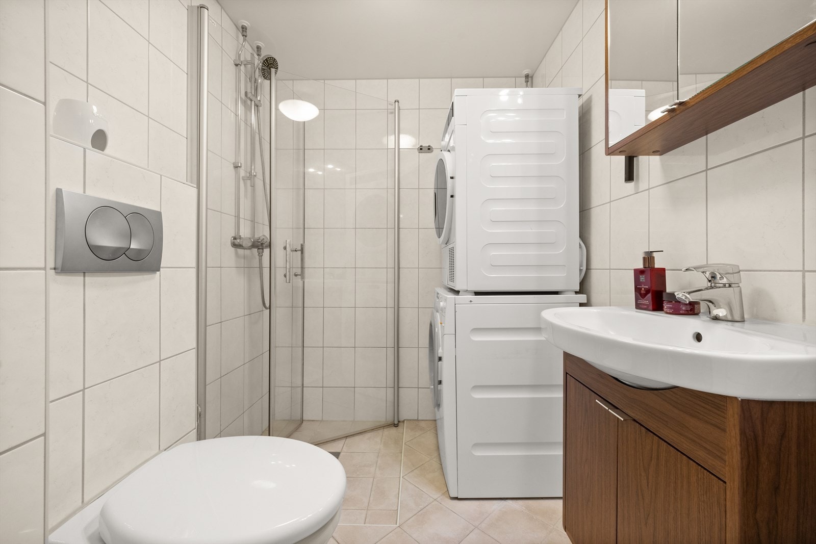 Flislagt bad med vegghengt toalett, dusjhjørne og servant - samt opplegg for oppvaskmaskin Galleribilde