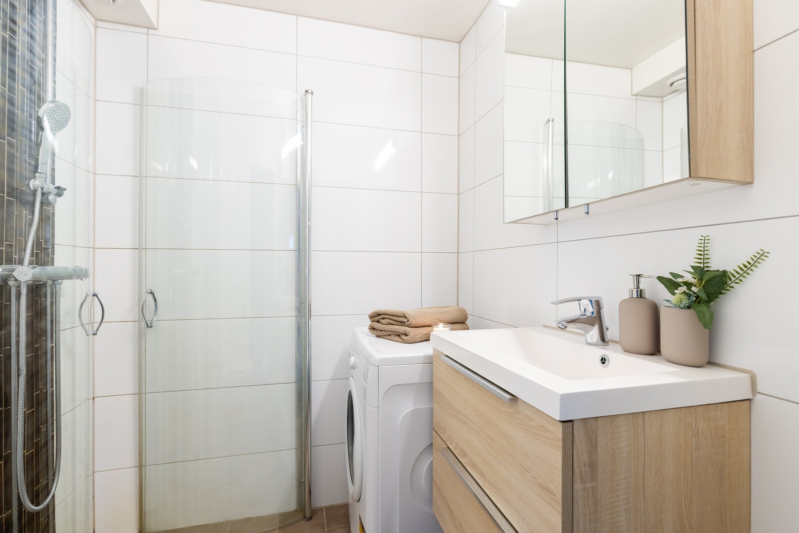 Badet er utstyrt med innredning med nedfelt servant, veggmontert toalett og dusjvegger/hjørne. Galleribilde