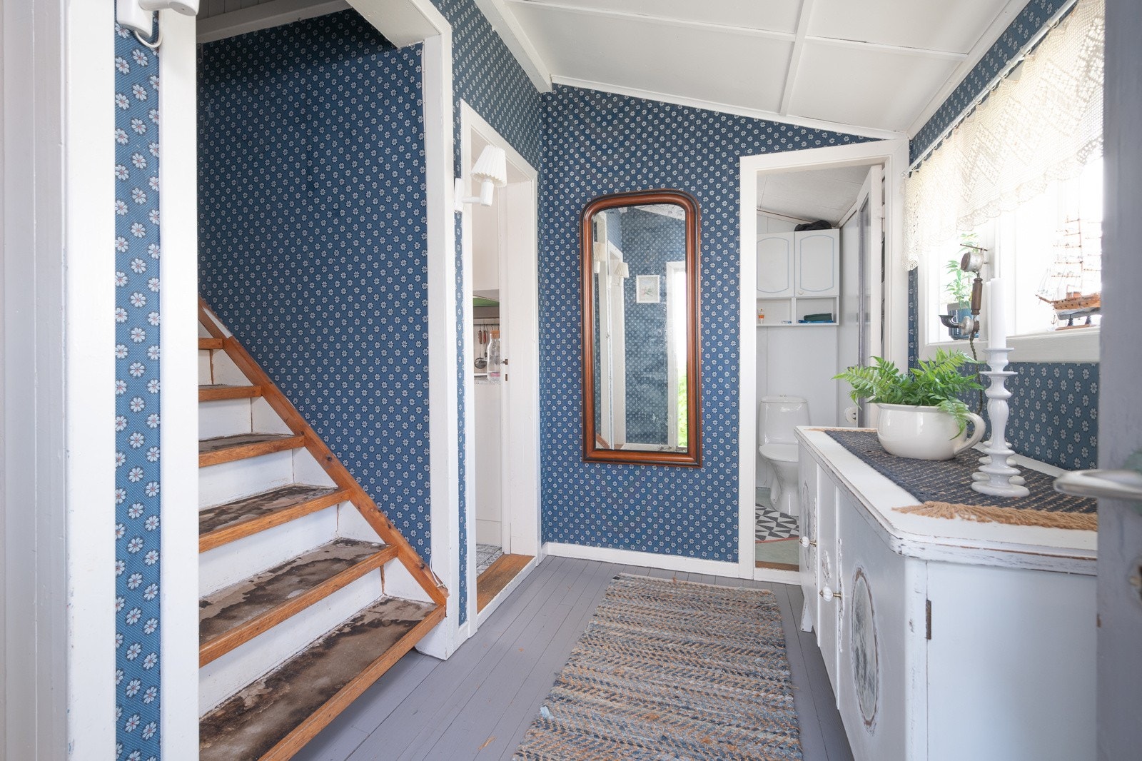 Entré med malt tregulv, tapet og lukket trapp til loft Galleribilde