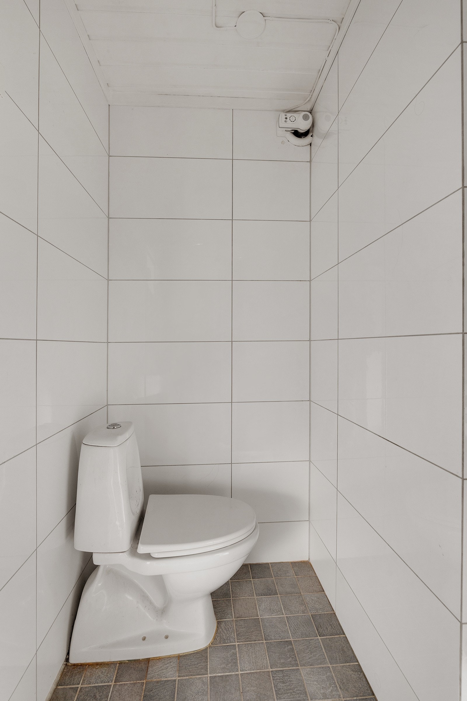 Badet har gulvstående toalett, servant med vegghengt servantskap, og en dusjsone med dusjforheng. Galleribilde