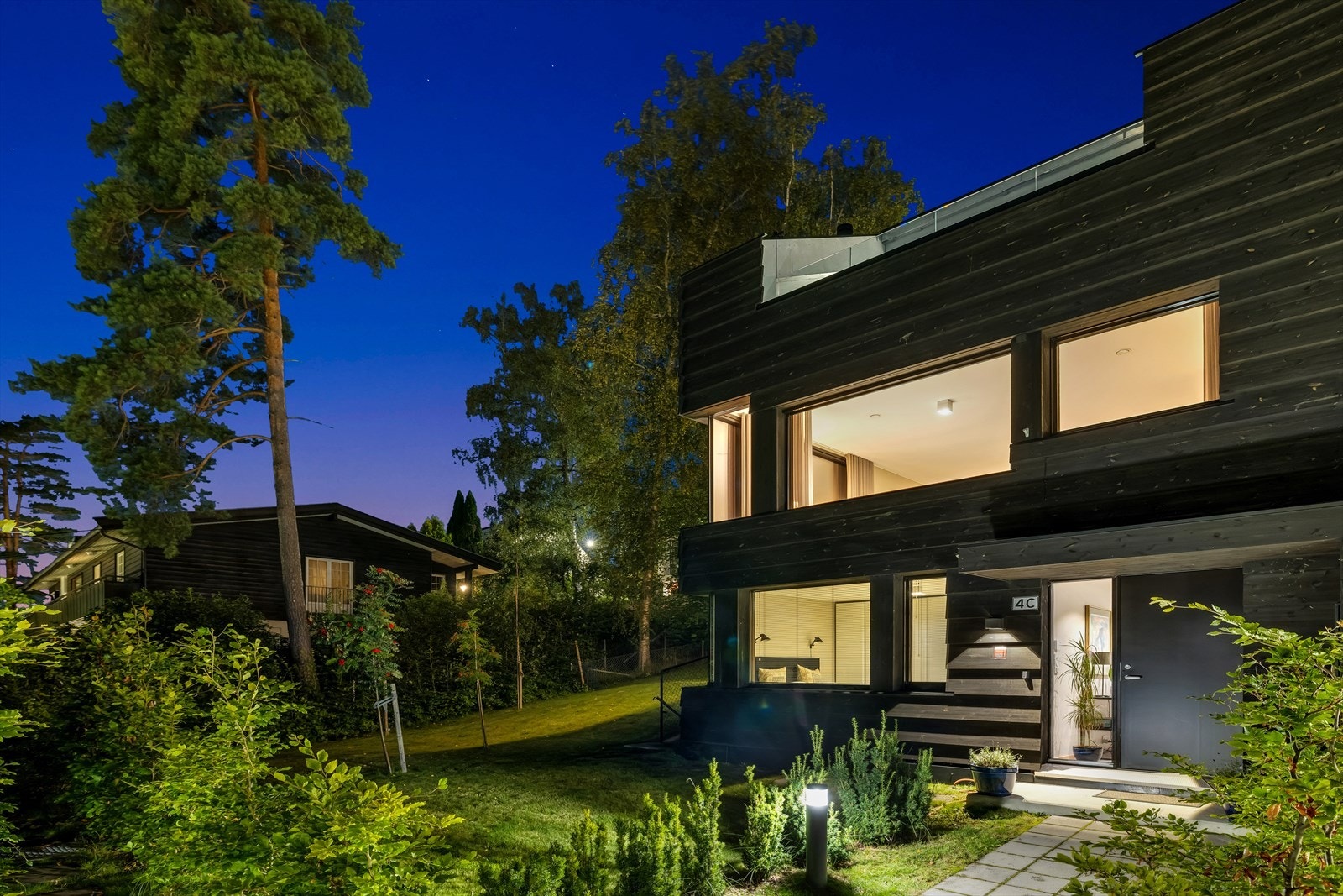 Flott opparbeidet inngangsparti med steinheller, beplantning og belysning. Galleribilde
