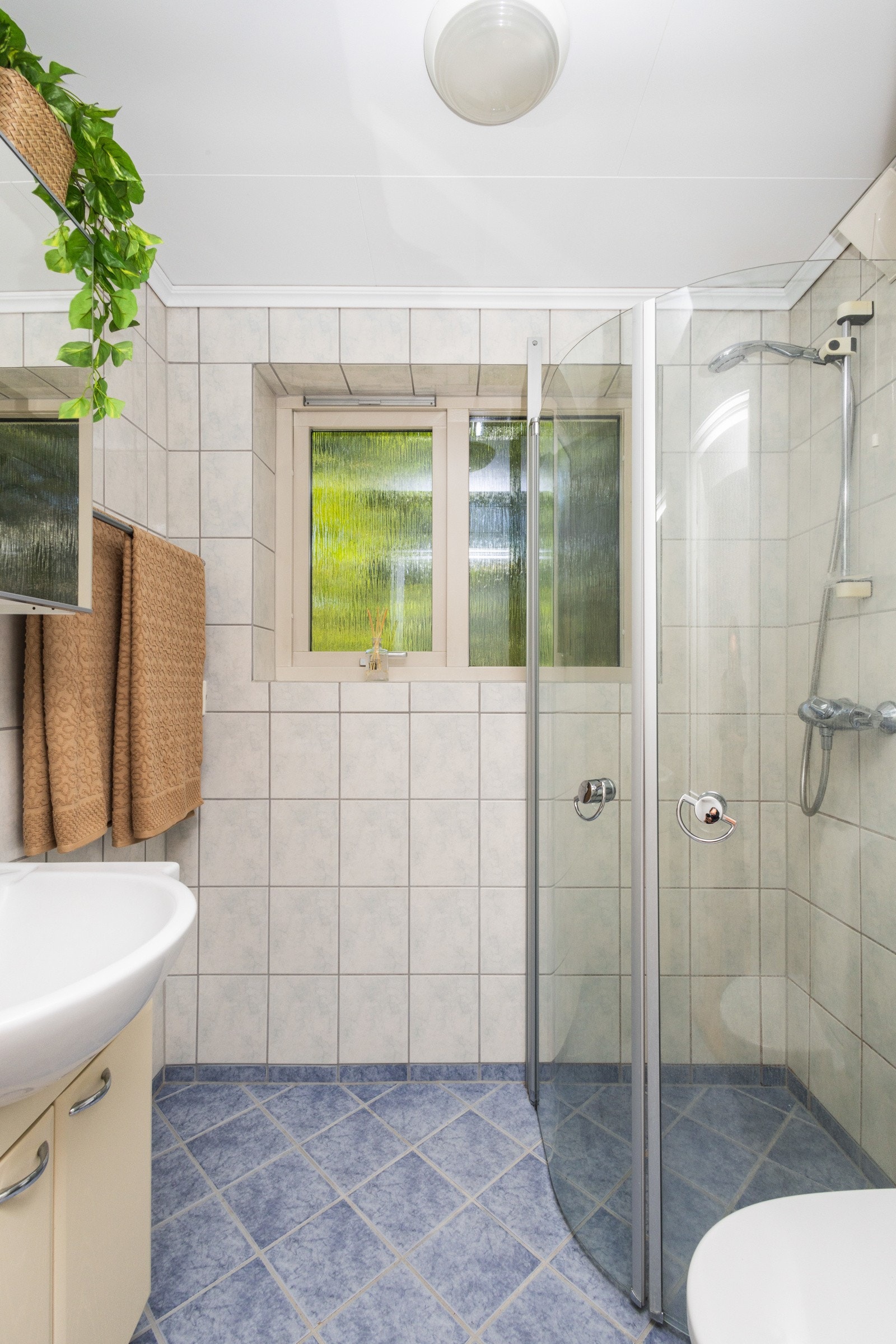 Badet er flislagt og har naturlig lys inn gjennom vindu på endevegg Galleribilde