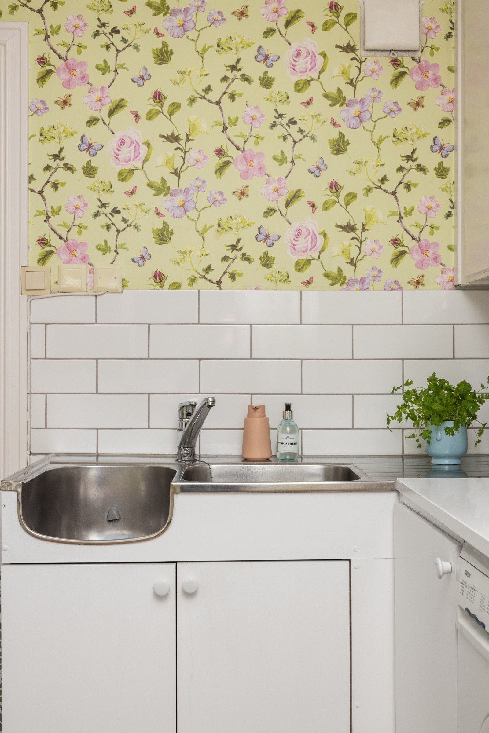Kjøkkenet har metrofliser over benk og en glad, blomstret tapet Galleribilde