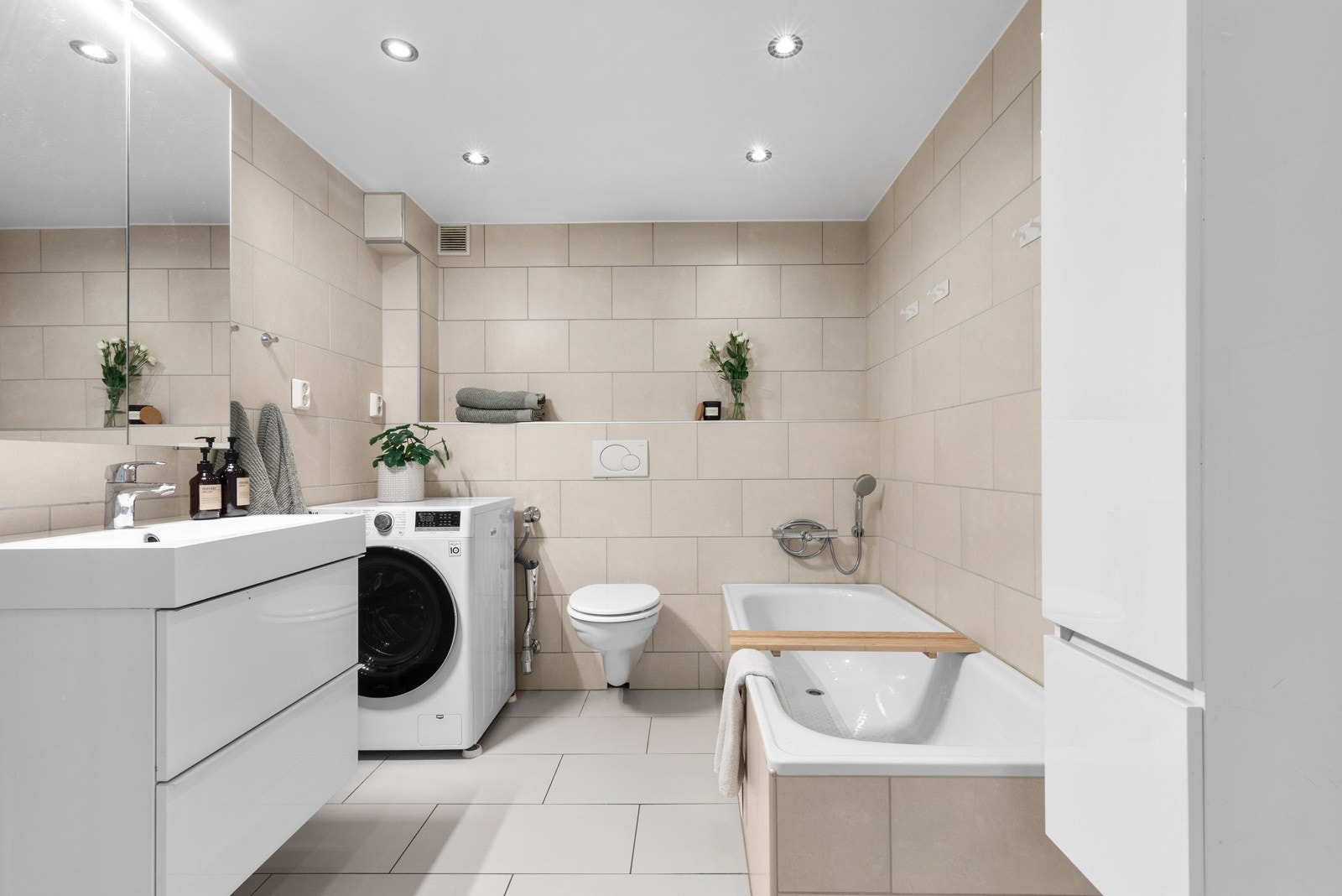 Bad fra 2012 med flislagt, innebygd badekar, dusjhjørne og opplegg for vaskemaskin. Galleribilde