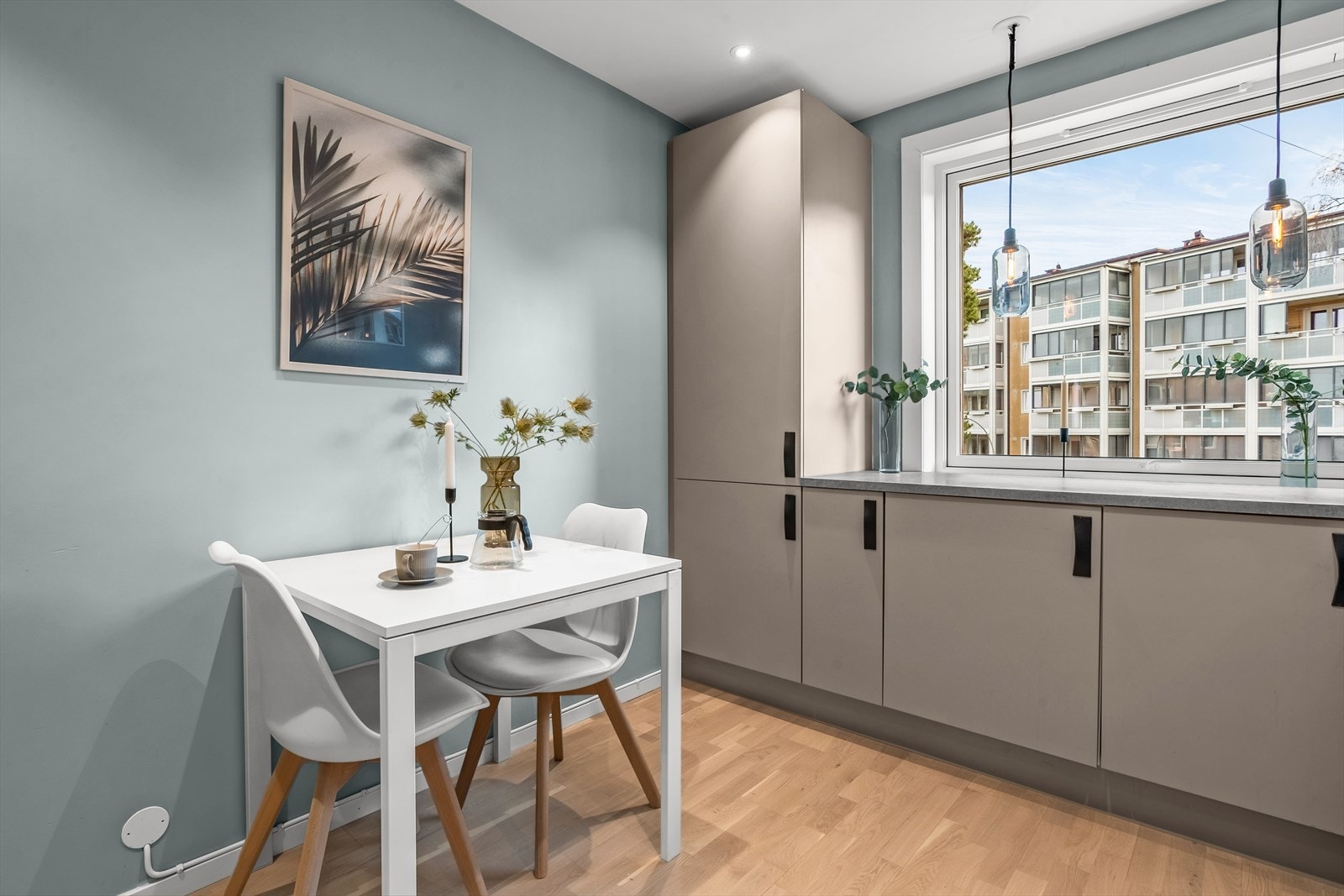 Adskilt kjøkken med plass til frokostbord, her kommer morgensolen inn. Kjøkkenet har senket himling med downlights og høyttalere. Veggen mot nabo ble lydisolert i forbindelse med oppussing av rommet. Galleribilde