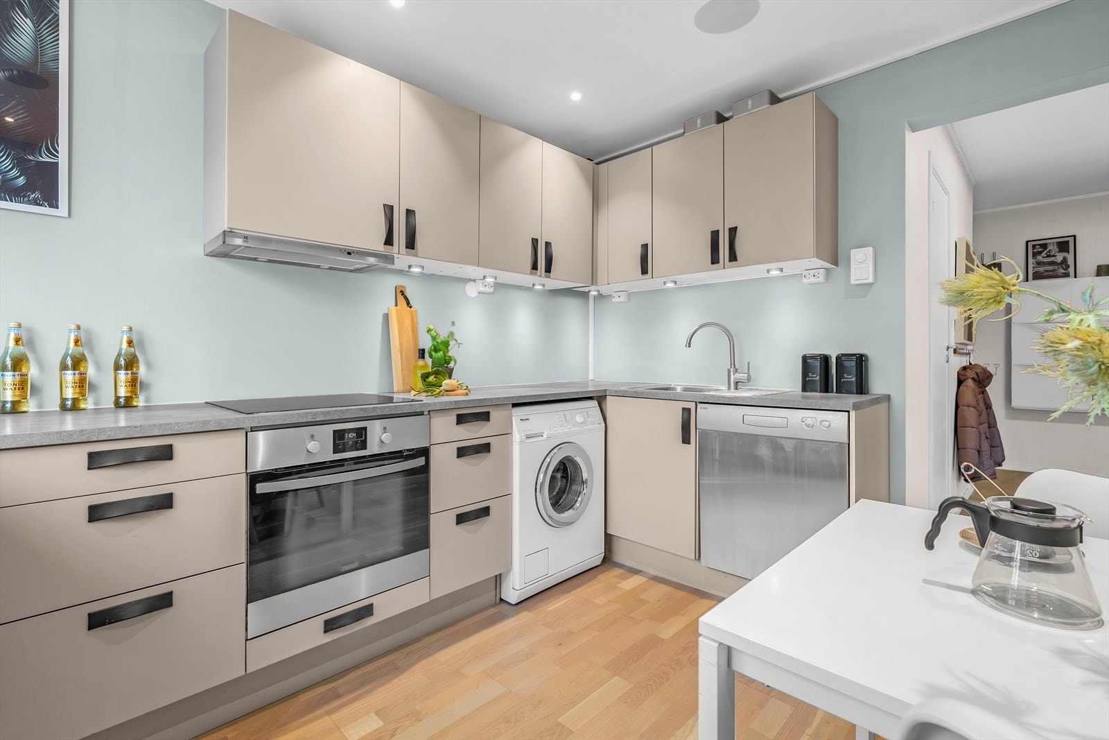 Lekker HTH kjøkkeninnredning fra 2016 med glatte fronter, belysning under overskap, laminat benkeplate med nedfelt kum i rustfritt stål og ventilator. Hvitevarer som stekeovn og kjøl-/fryseskap er integrert i innredningen. Galleribilde