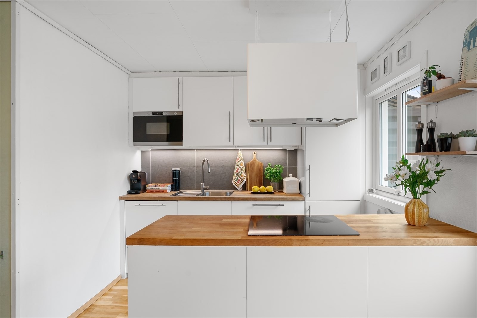 Det er lagt fliser på vegg over benkeskap og belysning under overskap. Galleribilde