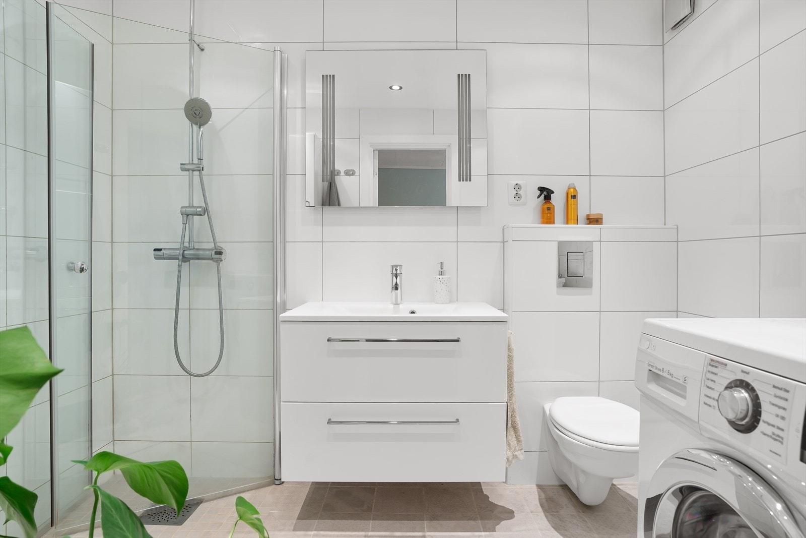 Pen innredning bestående av benkeskap med glatte fronter og speil. Dusj med innfellbare dører i herdet glass, servant og veggfestet klosett. Galleribilde