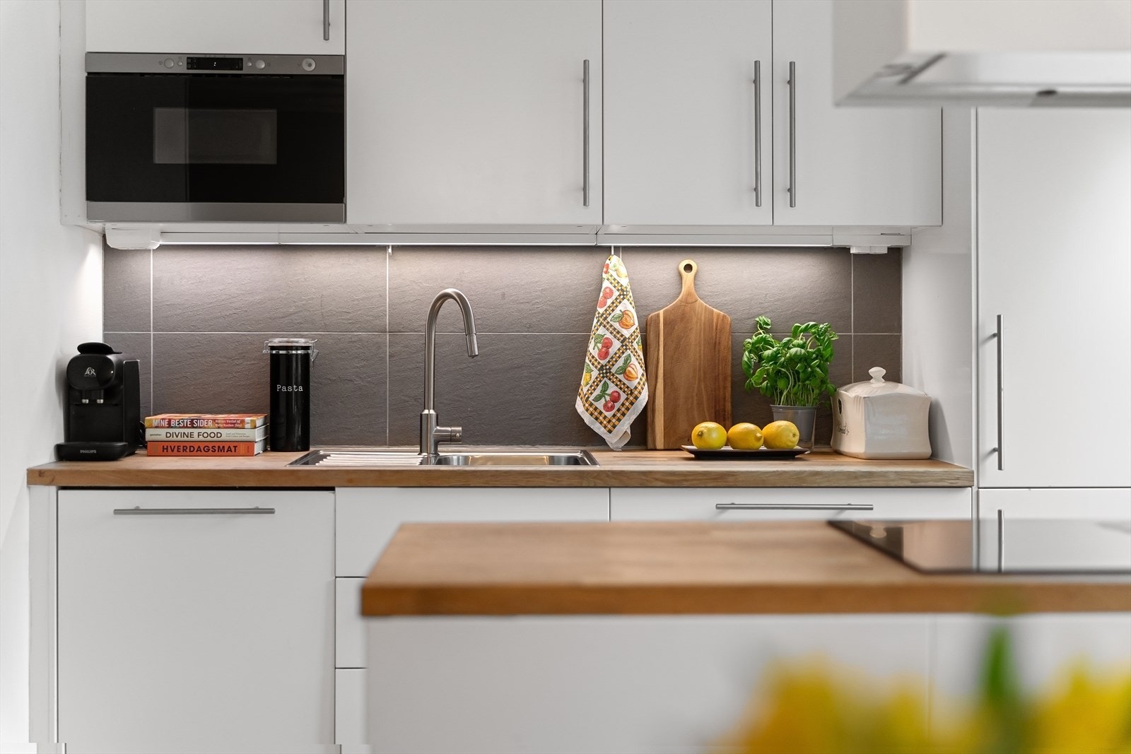 Integrerte hvitevarer som induksjonstopp, stekeovn, oppvaskmaskin, mikrobølgeovn og kjøl/frys. Galleribilde