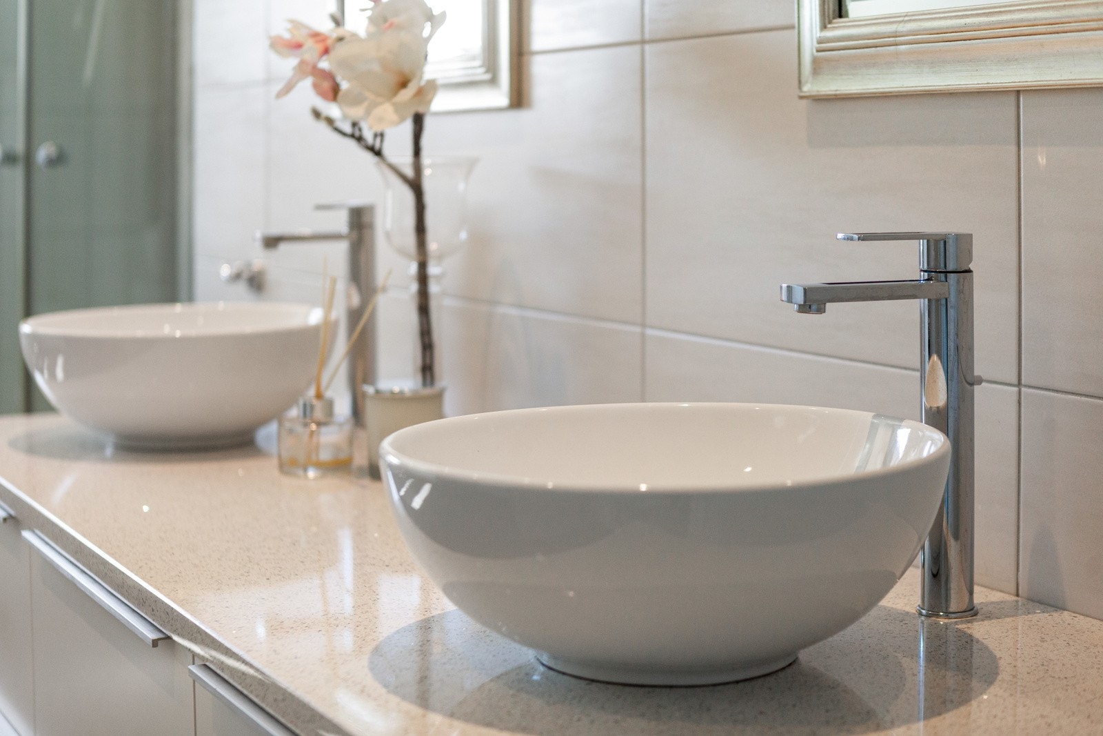 Innredningen består av en hvit skuffeløsning med to toppmonterte servantskåler på en Silestone benkeplate - plassert under to elegante speil. Galleribilde