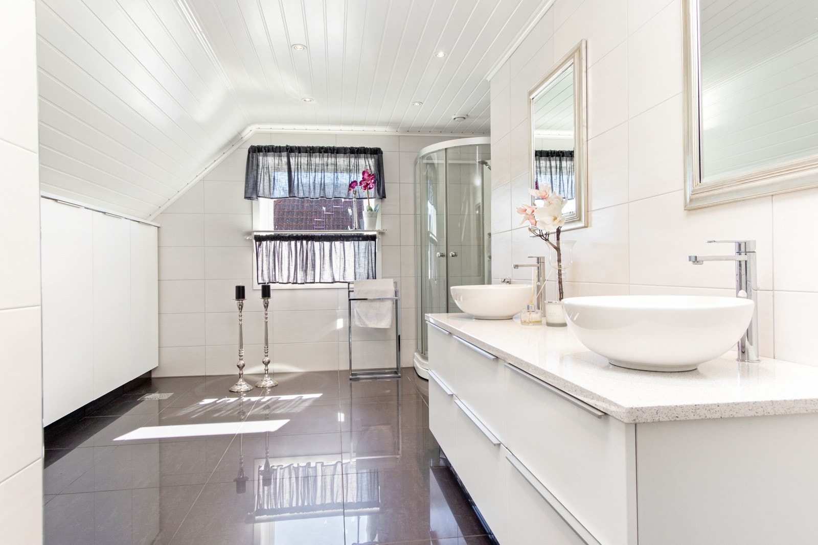 Badet oppe ble pusset opp i 2017 og har et stilrent uttrykk, der hvite veggfliser kombineres med store, grå gulvfliser. Galleribilde