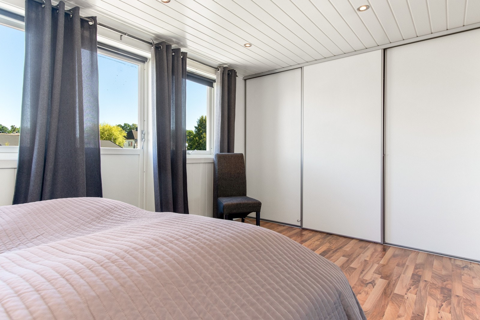 Hovedsoverommet har plass til dobbeltseng, og langs den ene veggen har rommet en stor og plassbygget skyvedørsgarderobe med hvite fronter. Galleribilde