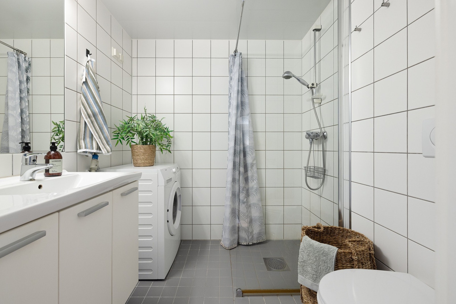 Flislagt bad/wc med hvit baderomsinnredning og opplegg til vaskemaskin. Godt med skapplass. Galleribilde