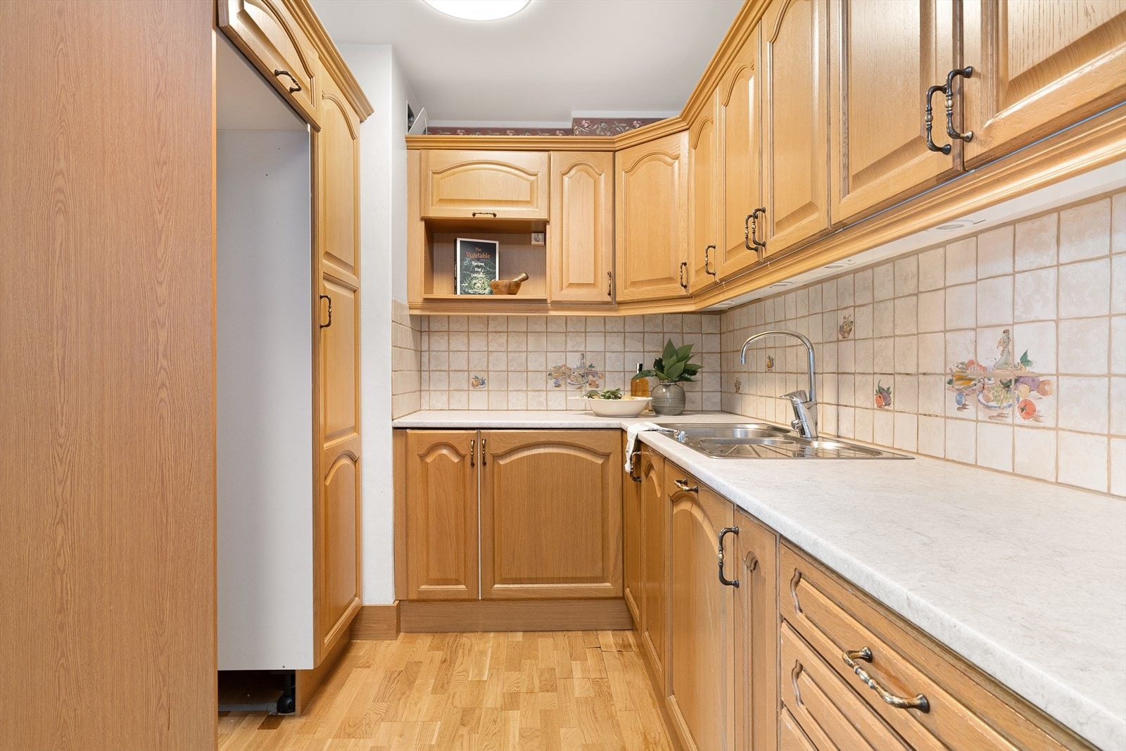 Kjøkkeninnredning med profilerte dører og laminat benkeplate. Kjøkkenet har plass til kjøleskap/frys, oppvaskmaskin, komfyr. Galleribilde