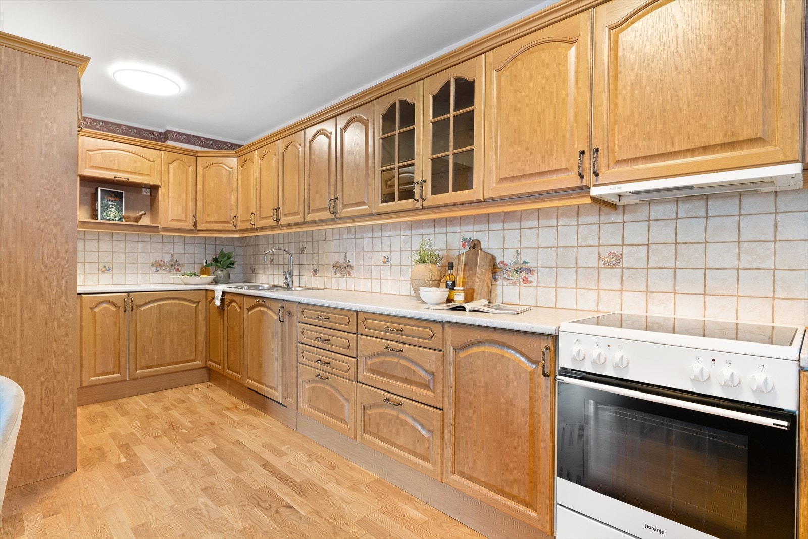 Romslig kjøkken med godt med skapplass , bra med benkeplass og fliser mellom benk og skap. Galleribilde