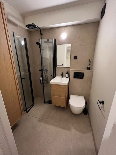 Moderne helfisert bad med dusjkabinett, vegghengt toalett og servant. Galleribilde