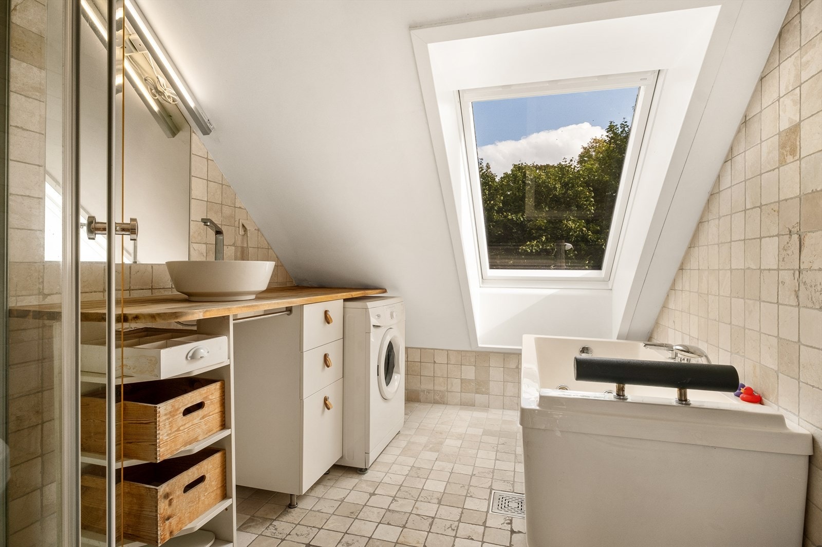 Stort bad med flislagte overflater og varmekabler i gulv. Det er servant i plassbygd innredning for maksimal romutnyttelse og speil med lys i rommet. Galleribilde