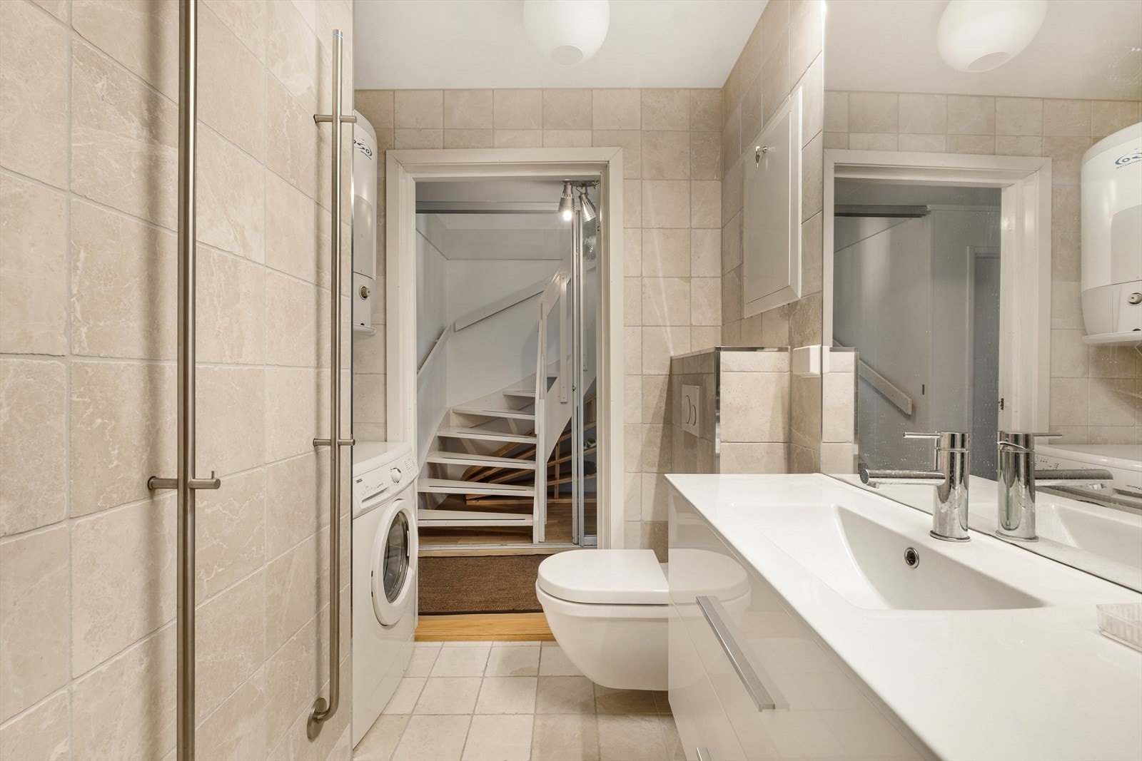 Videre er det innredet med vegghengt toalett, servant i innredning og opplegg til vaskemaskin. Det er sluk med tilhørende vannlås, fra 2017. Synlig banemembran og klemring i sluket. FDV-dokumentasjon på utførelse
foreligger. Galleribilde