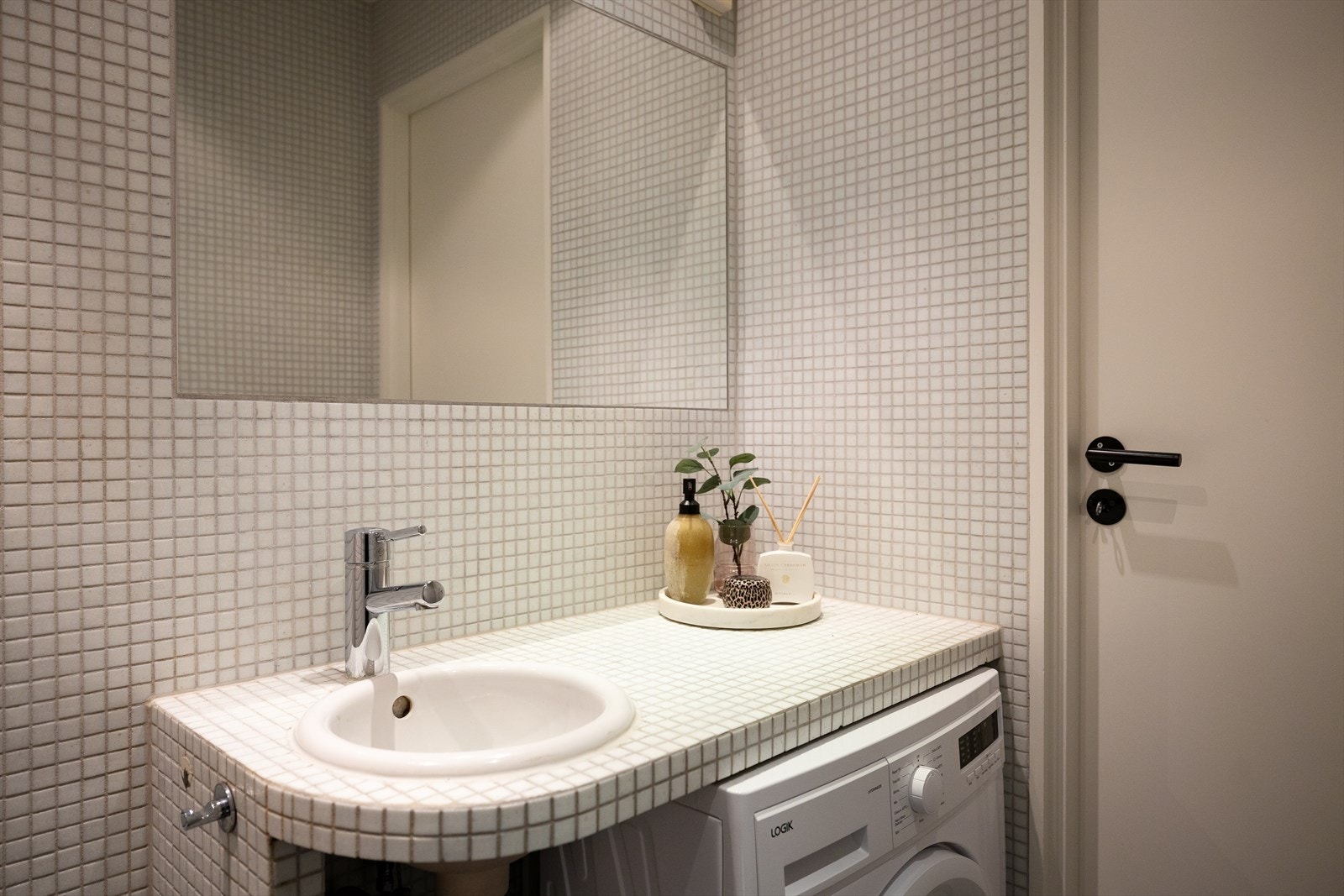 Badet er innredet med vegghengt toalett med innebygd sisterne, en plassbygd benkeplate med servant og ett-greps blandebatteri, samt dusjhjørne Galleribilde