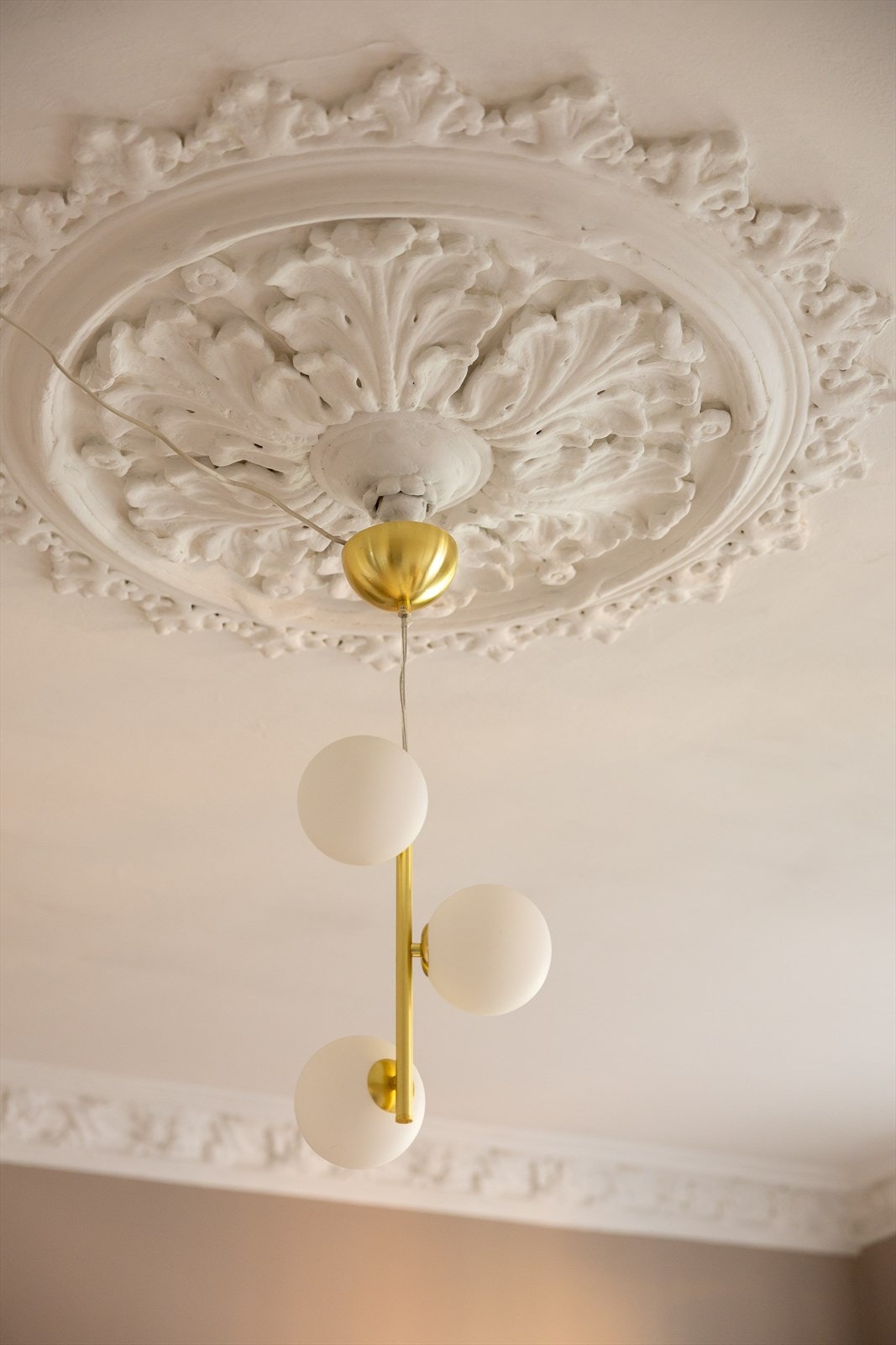 Legg merke til de klassiske detaljene i leiligheten - elegant stukkatur og rosett i himlingen tilfører rommet et tidløst preg Galleribilde