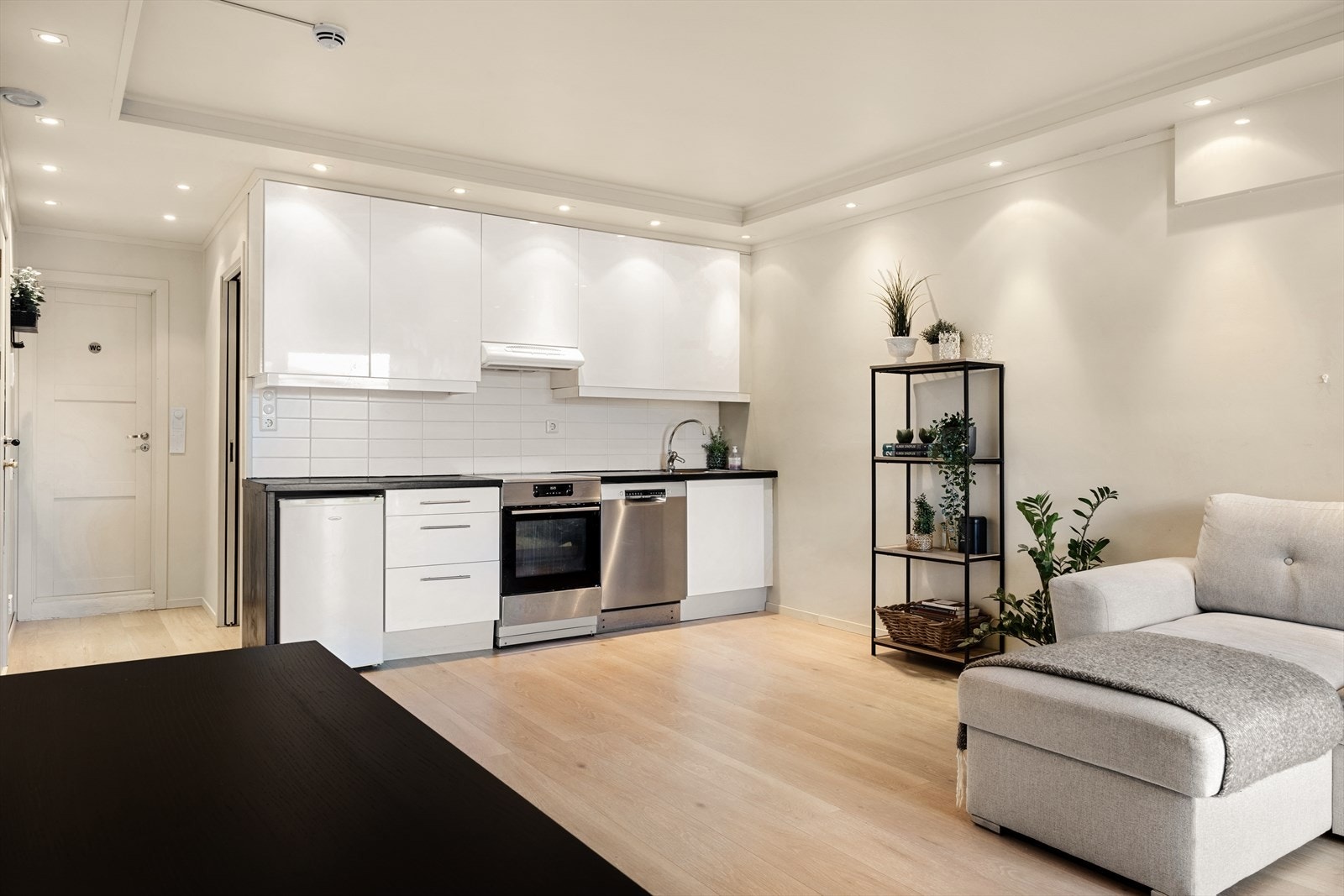 Åpen løsning gir fullt innsyn fra stue til kjøkken og birdrar til å skape en sosial atmosfære Galleribilde