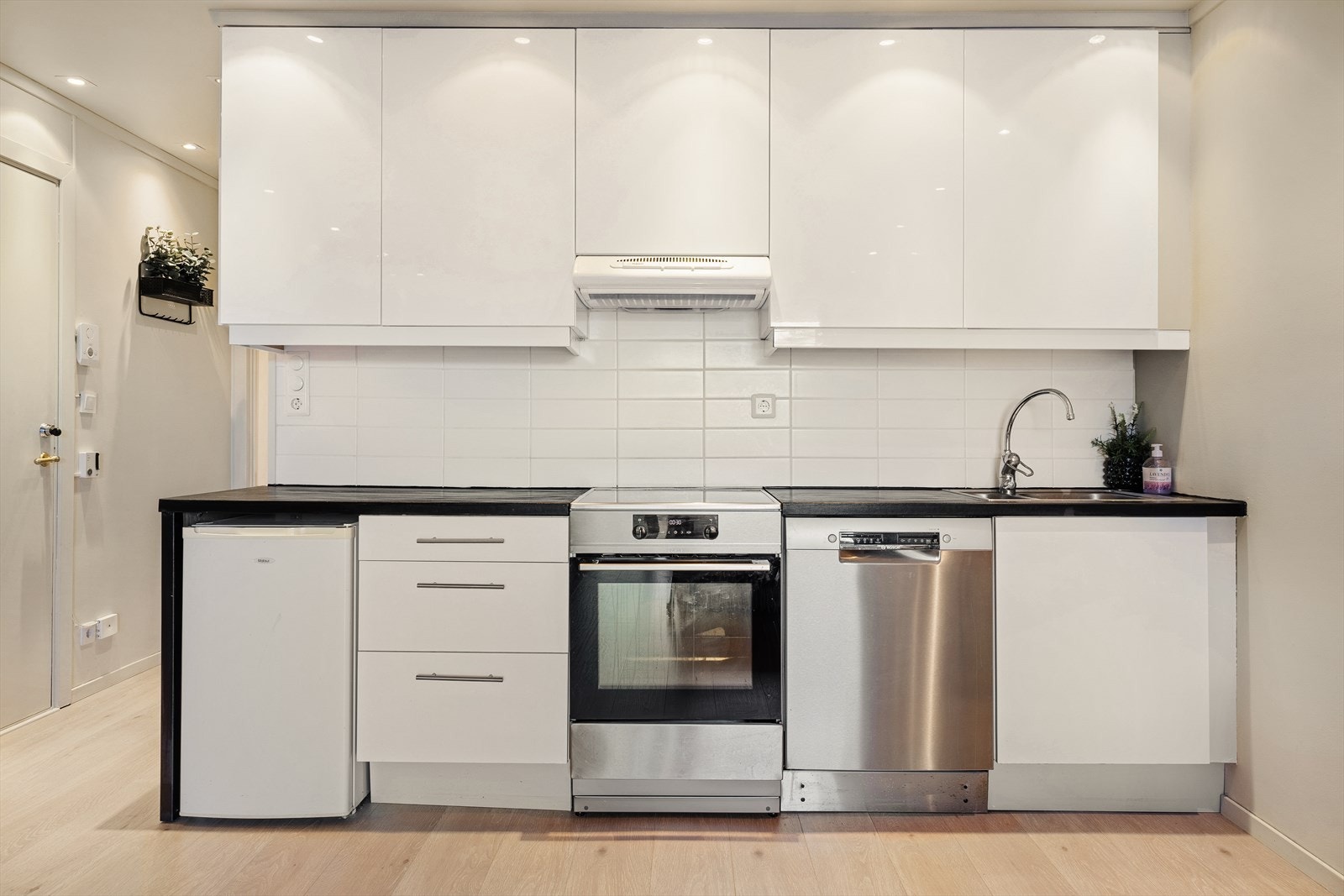 Tidsriktig kjøkkeninnredning med slette fronter, heltre benkeplate, stål oppvaskkum og ventilator Galleribilde