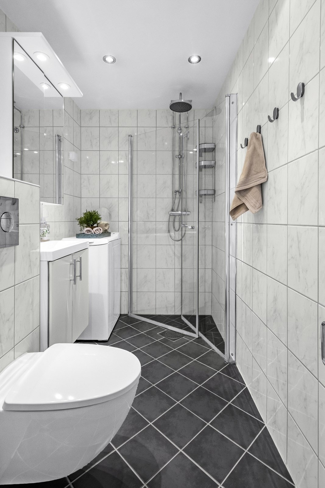 Baderommet er utstyrt med servant med innredning, dusjnisje med regnfallsdusj og vegghengt toalett Galleribilde