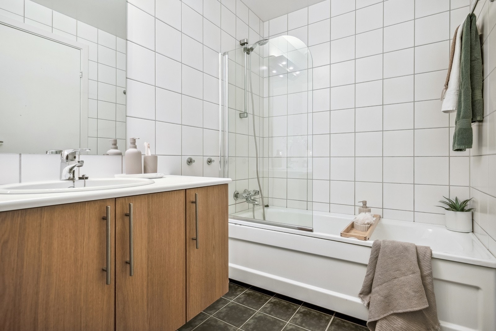 Etasjens bad er flislagt og utstyrt med badekar, vegghengt toalett og en romslig baderomsinnredning med mye oppbevaringsplass. Galleribilde