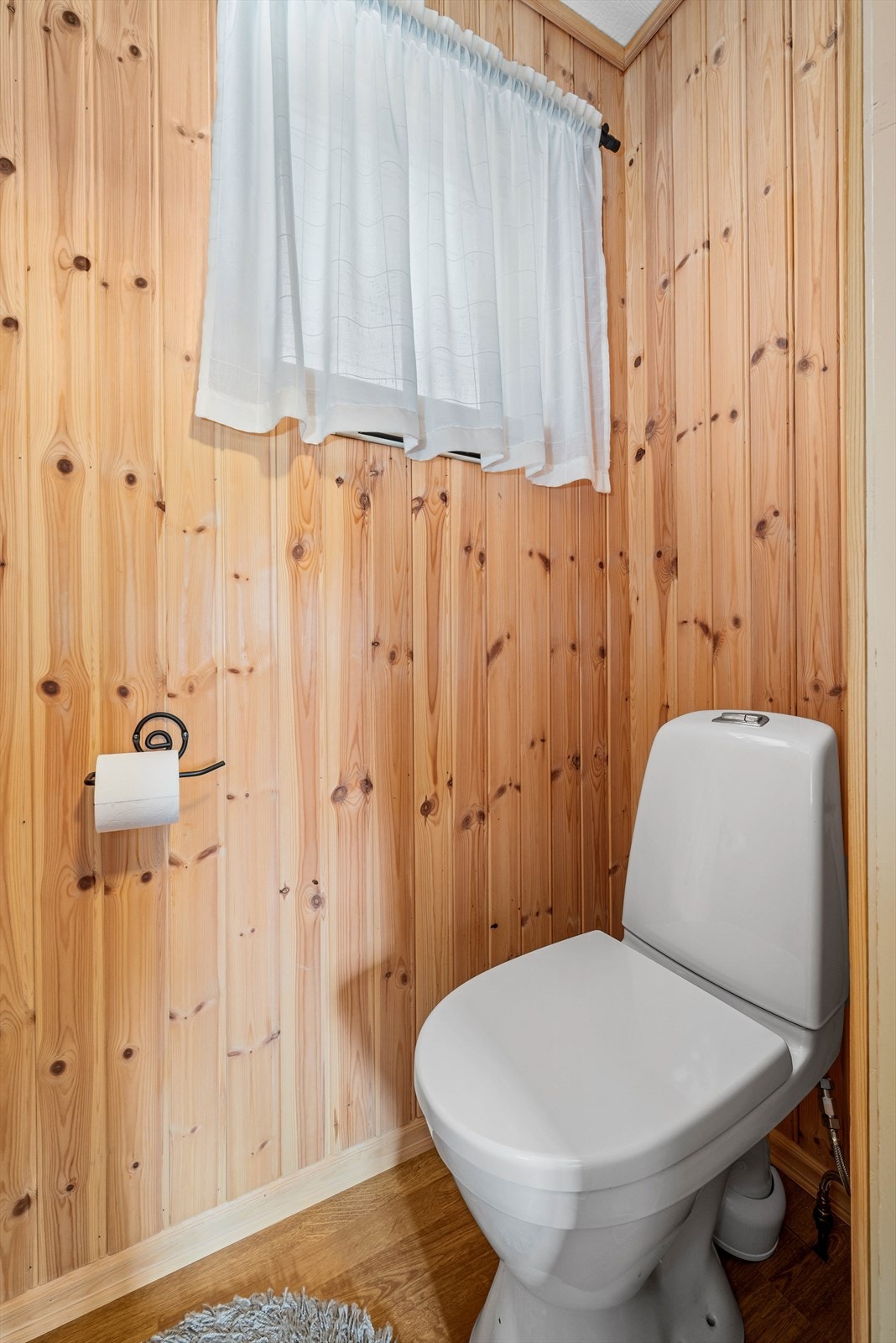 Boligen har to toalettrom, ett i hver etasje og begge i samme stil med gulvstående toalett og panel på vegger. Galleribilde