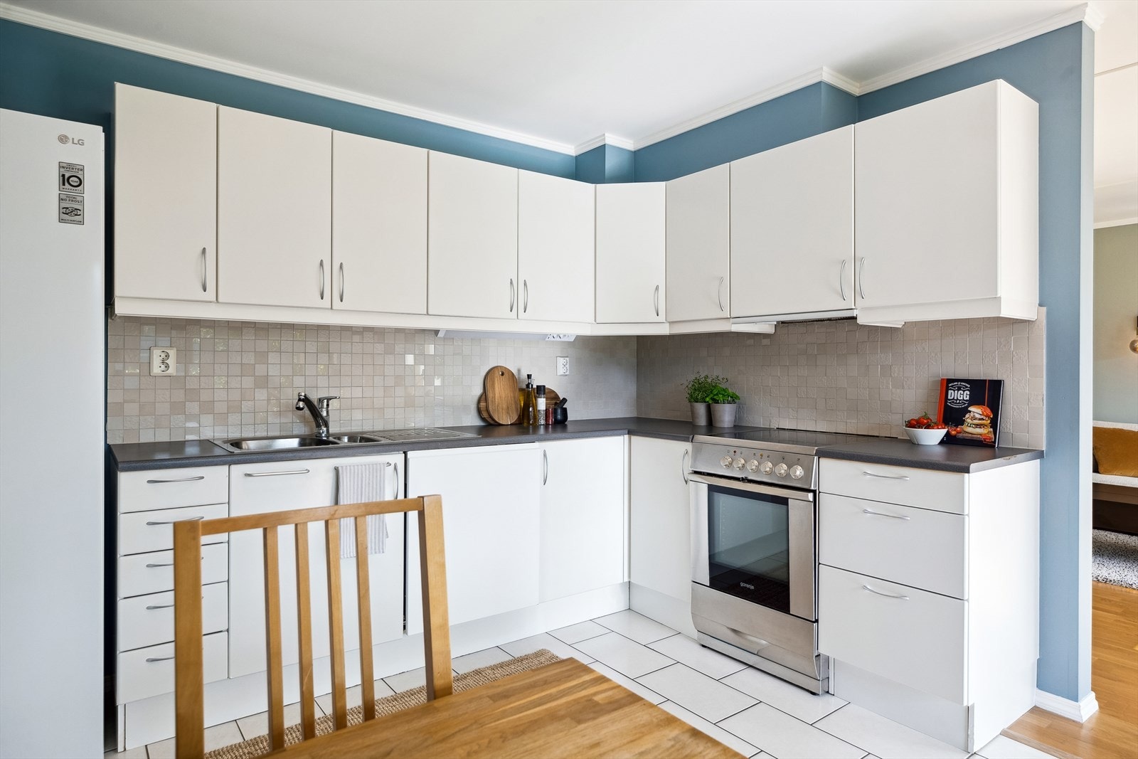 Den vinkelformede innredningen er angitt med TG1 av takstmann, og byr på rikelig med skap- og benkeplass. Videre er det fliser på gulv, samt mellom over- og underskap. Stekeovn og oppvaskmaskin vil medfølge. Galleribilde