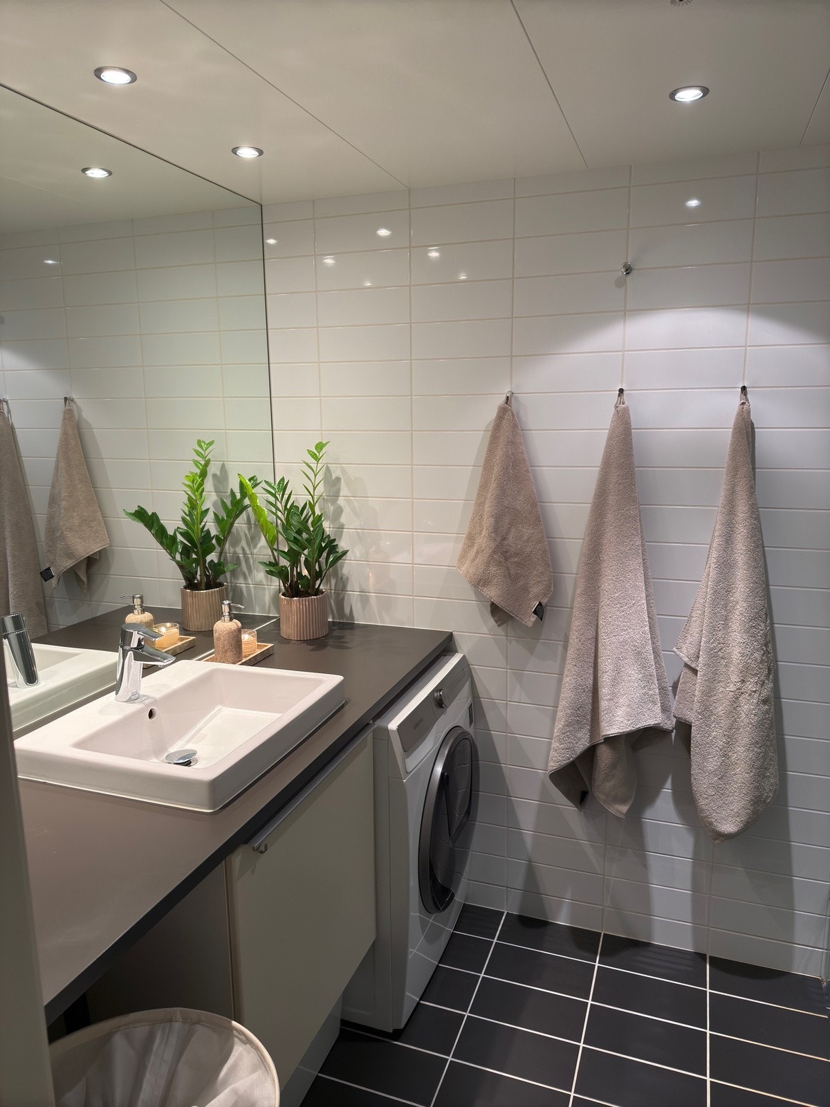 Flislagt bad med dusjhjørne, innfliset speil, vegghengt toalett og servant med underskap. Galleribilde